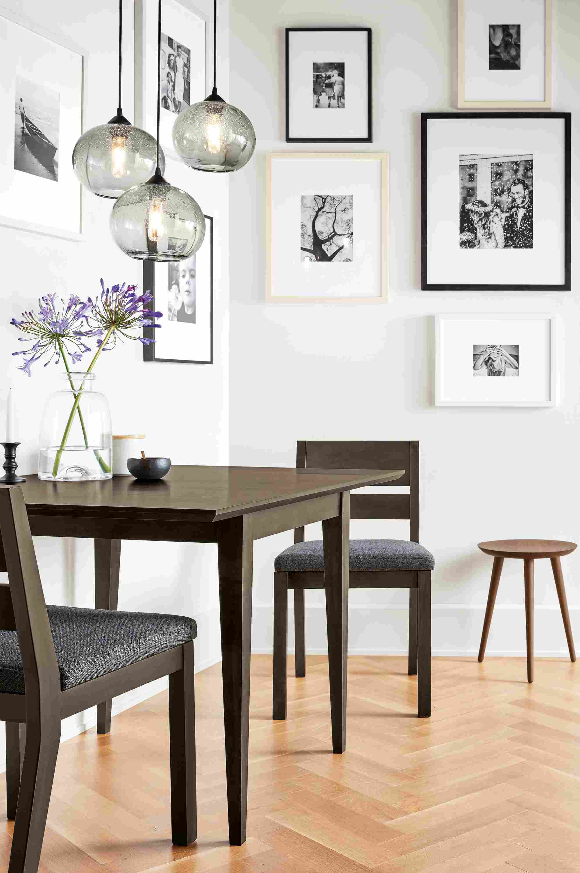 Detail view of 3 Abra smoked-glass globe pendants over an Adams table in charcoal a dining area.