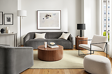 Living room with 90-wide ada sofa in vance gray fabric, ada swivel chair, novato chair, liam wood veneer accent tables.