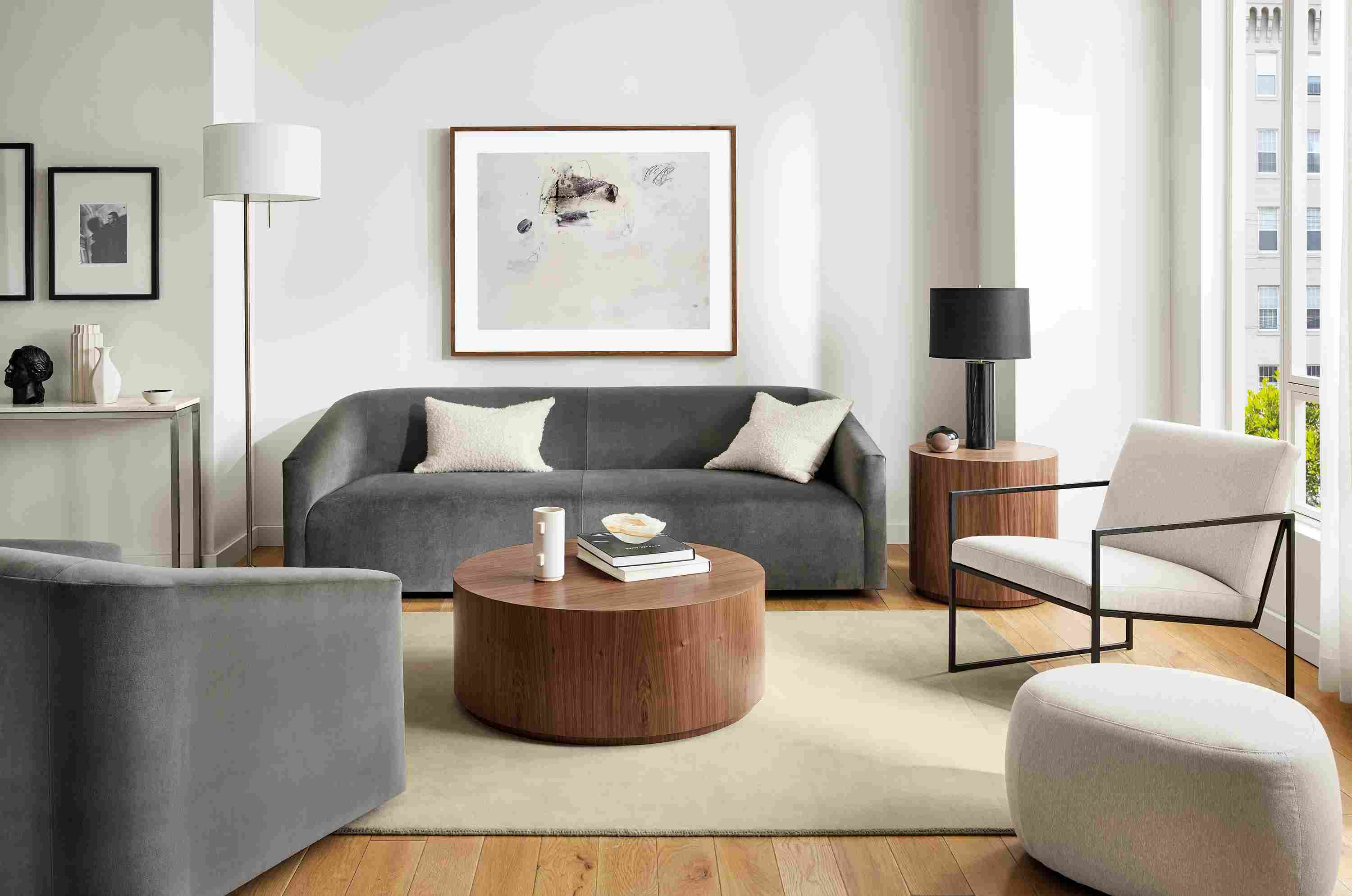 Living room with 90-wide ada sofa in vance gray fabric, ada swivel chair, novato chair, liam wood veneer accent tables.