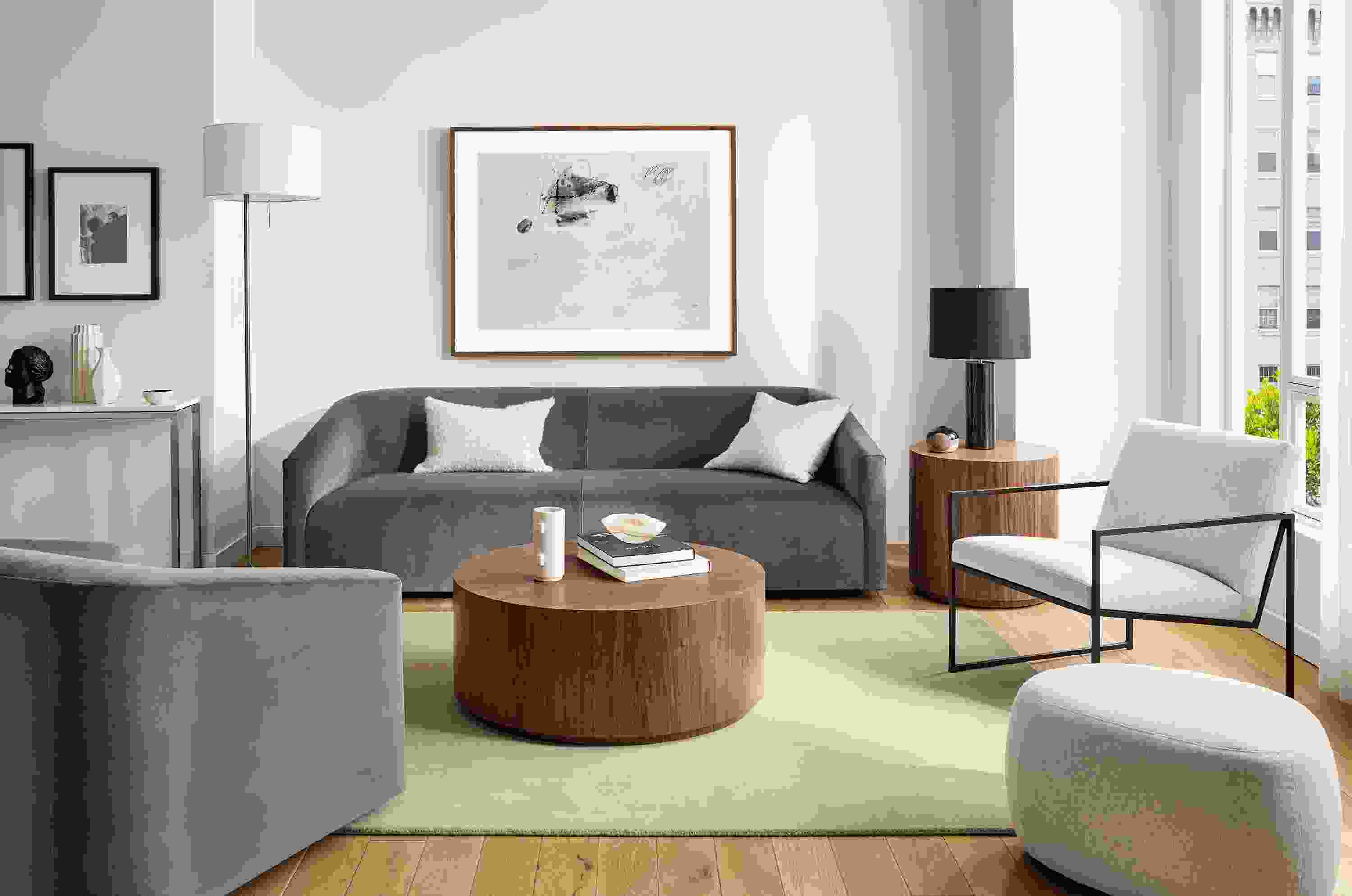 Living room with 90-wide ada sofa in vance gray fabric, ada swivel chair, novato chair, liam wood veneer accent tables.