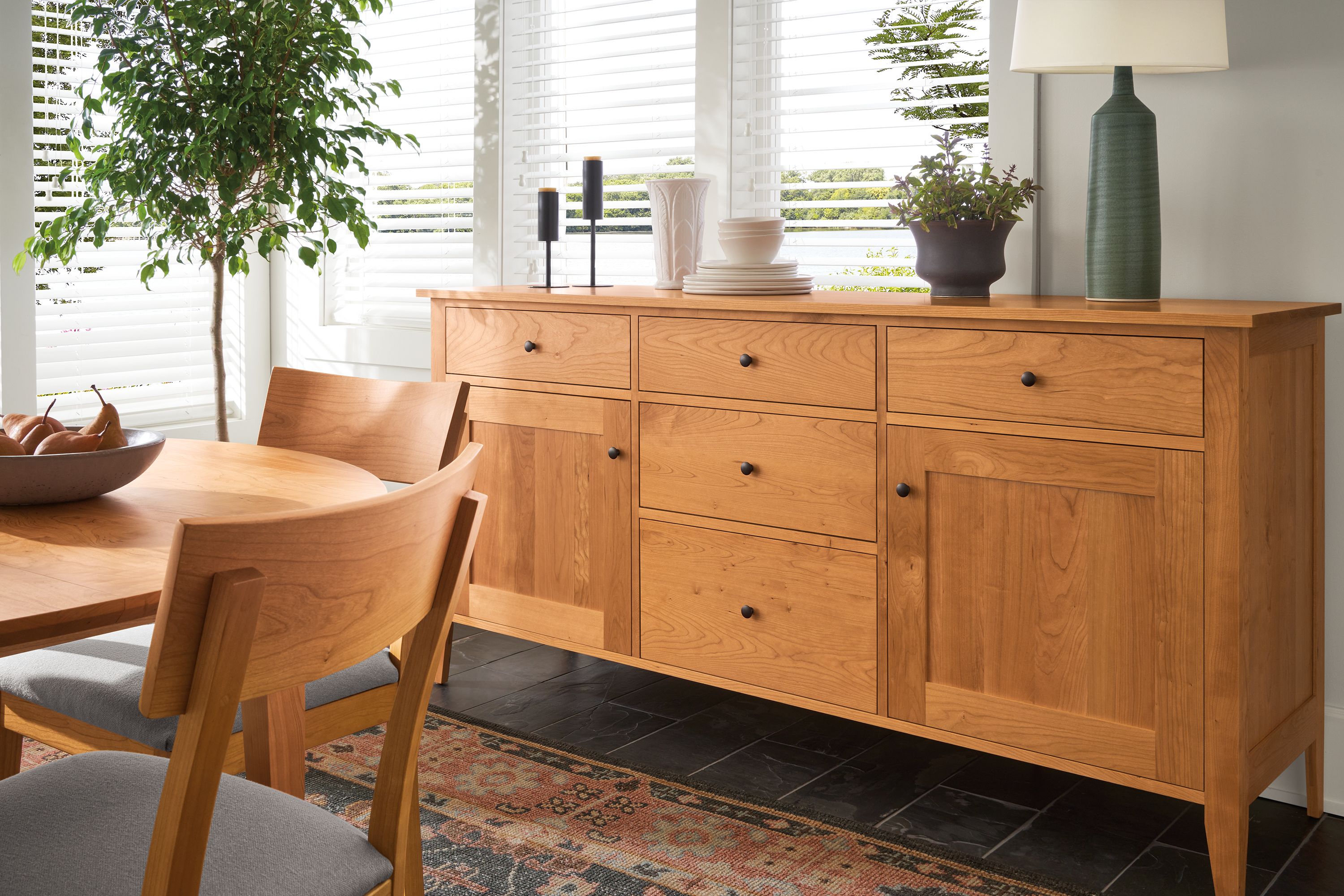 dining room with adams storage cabinet and dining table in cherry and doyle side chairs in cherry with fabric seats.