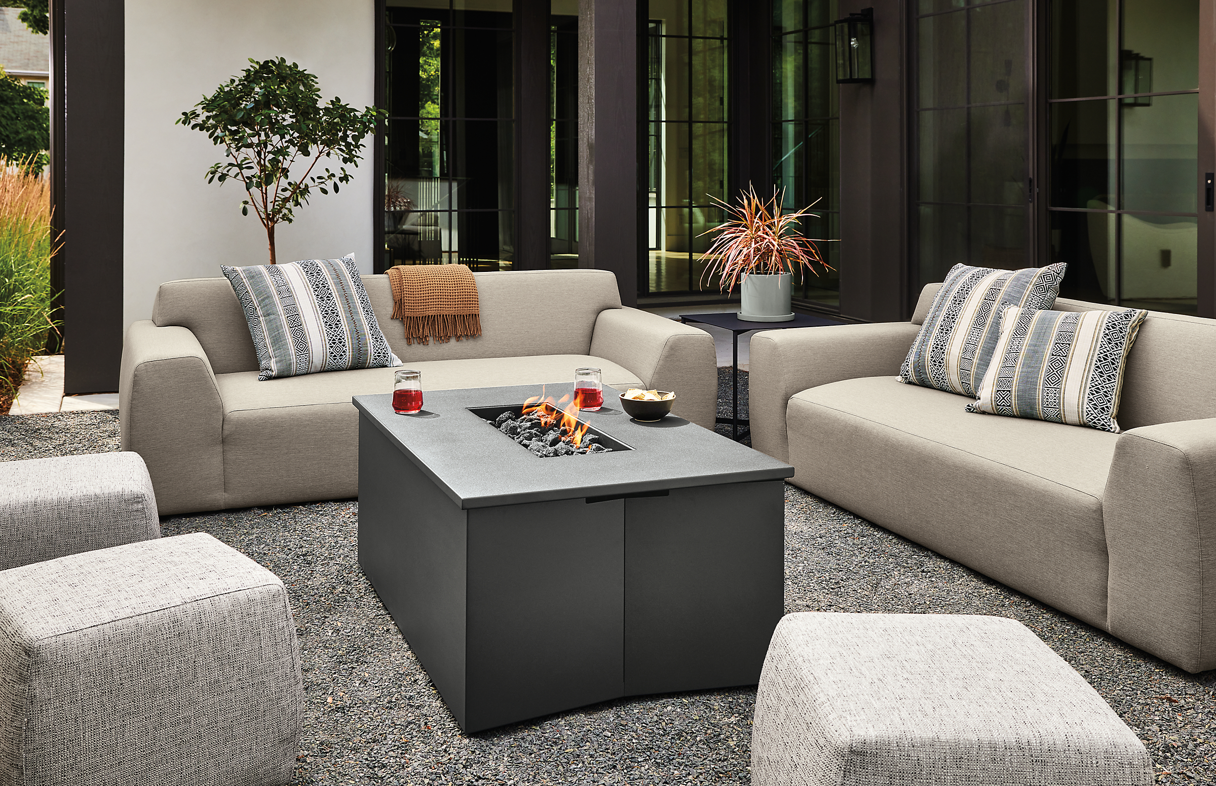 outdoor space with adara fire table lit, drift sofas, boyd ottoman.