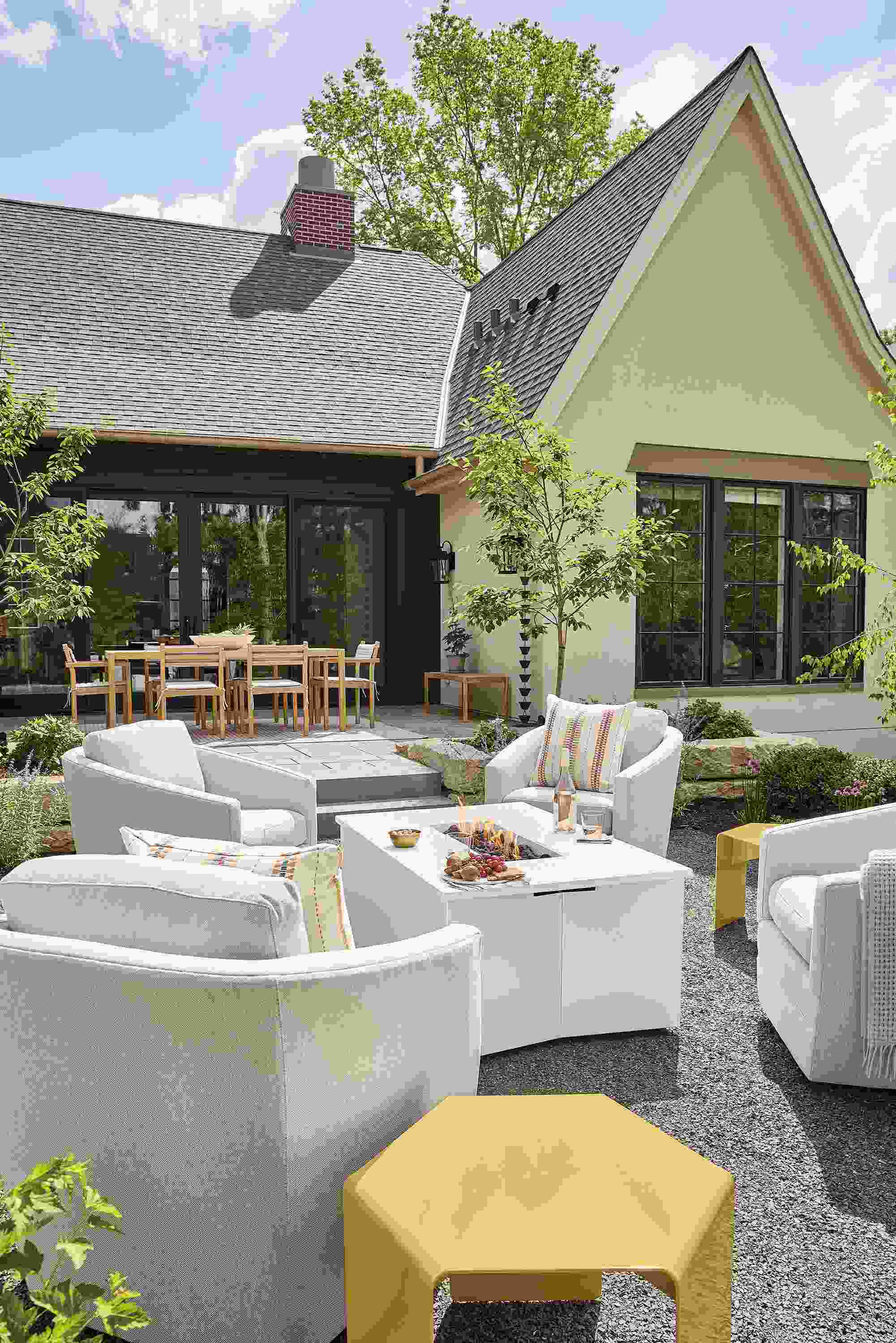 Outdoor seating area with lit adara propane fire table in white and 4 sunford swivel chairs in mist grey.