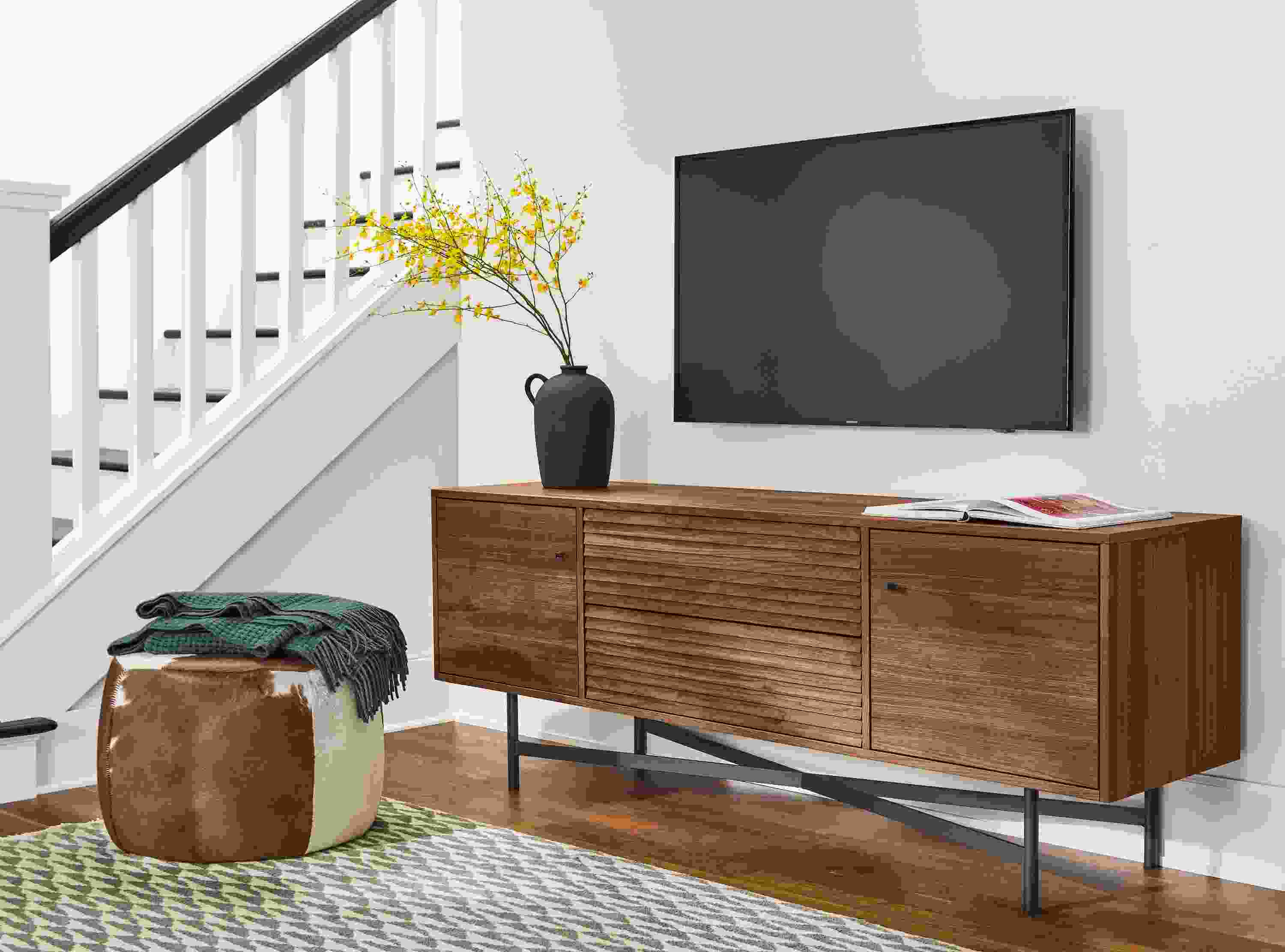 Living room with Adrian media cabinet in walnut and Lind ottoman in brown cowhide.