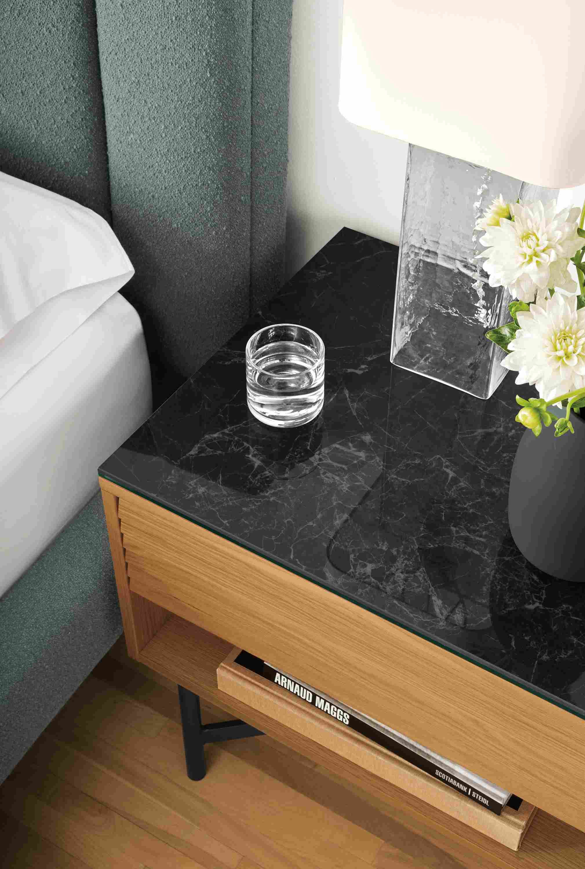 High-angle detail of Adrian nightstand in white oak with marbled black ceramic top in bedroom.