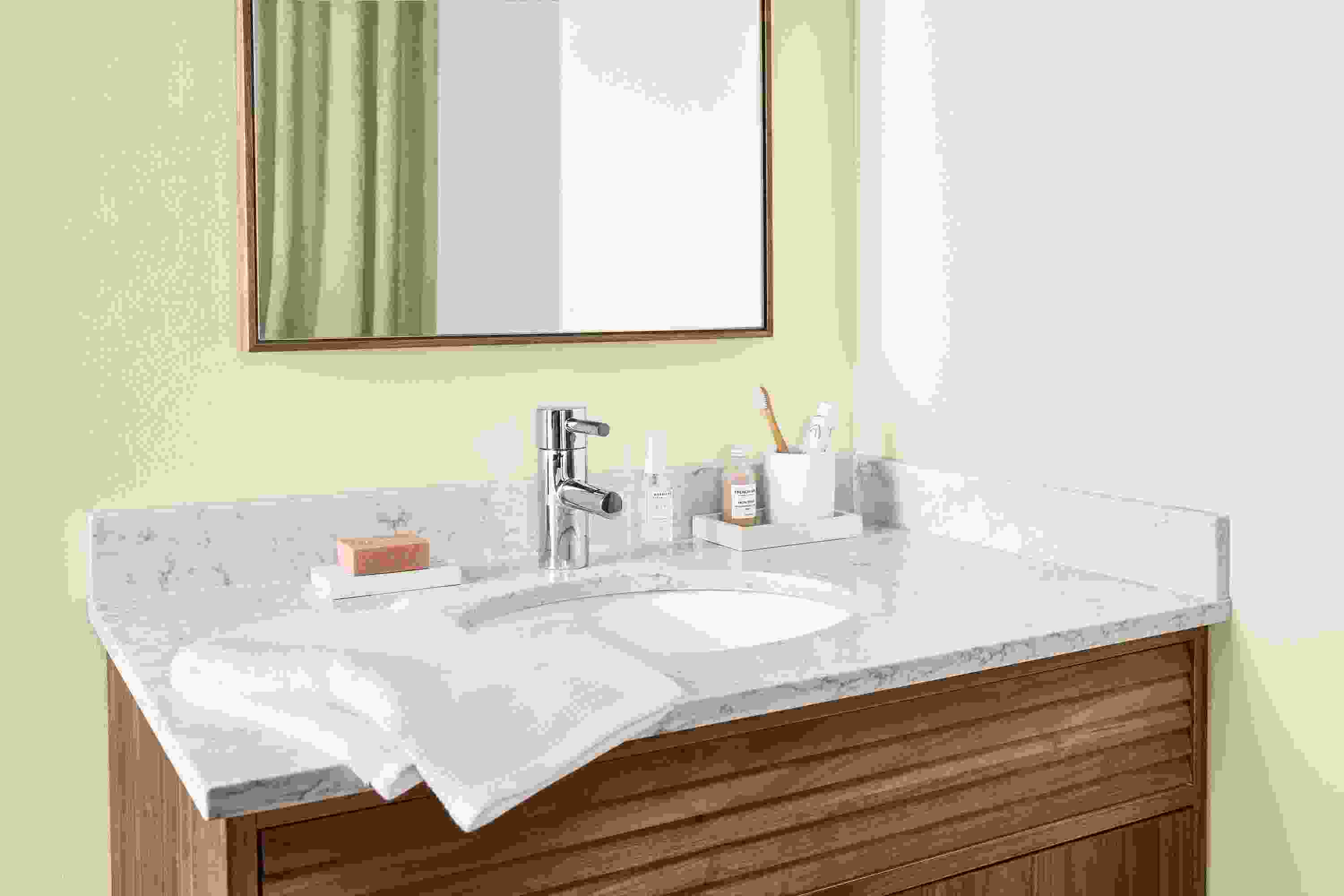 Bathroom with detail of Adrian vanity in walnut with marbled white quartz top.