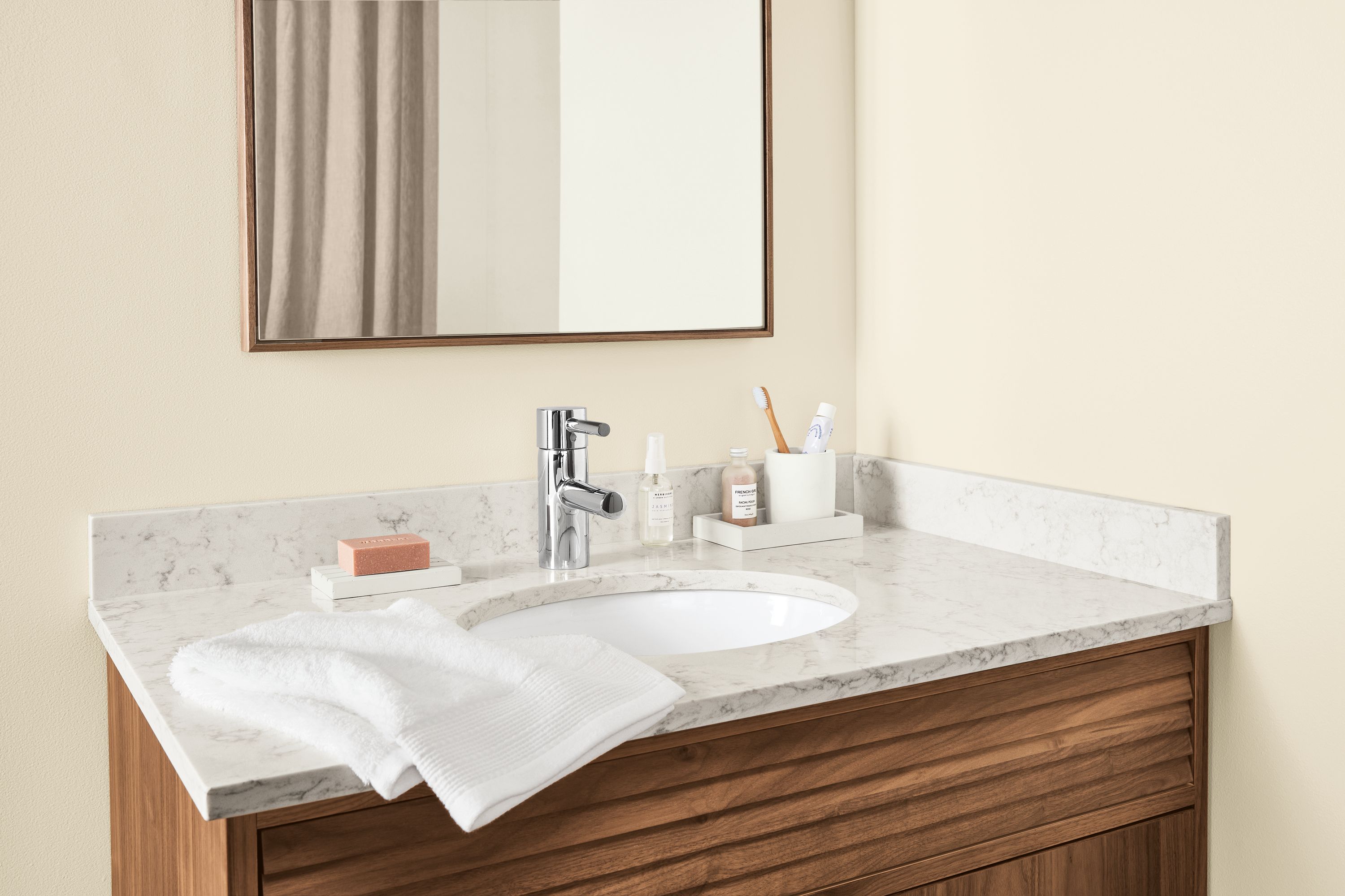 Bathroom with detail of Adrian vanity in walnut with marbled white quartz top.