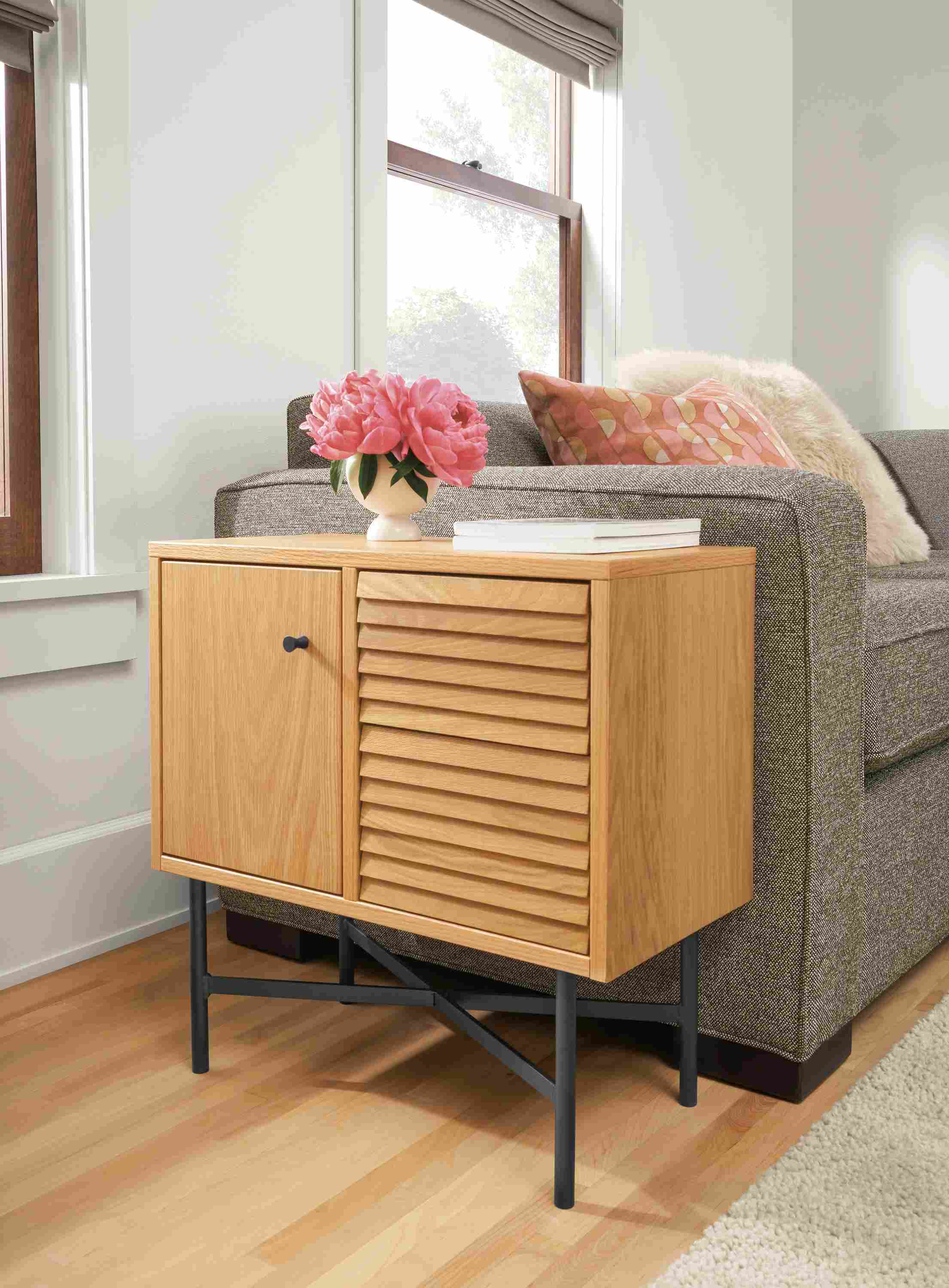Detail of Adrian storage cabinet in white oak beside Ian sectional sofa in tatum mink in living room.