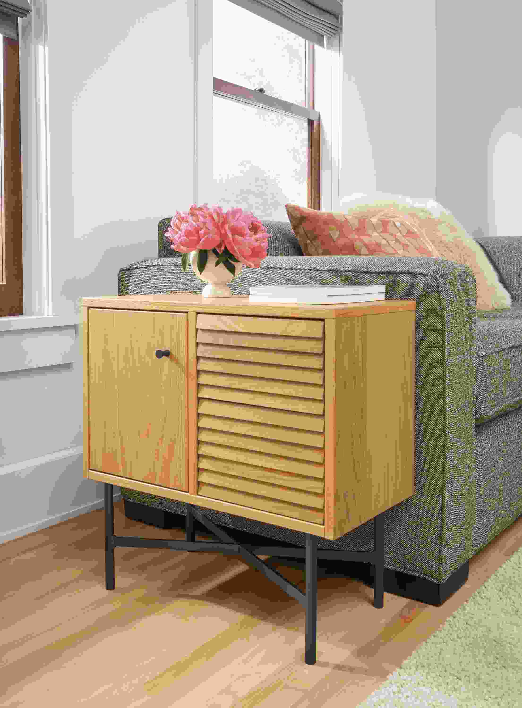Detail of Adrian storage cabinet in white oak beside Ian sectional sofa in tatum mink in living room.
