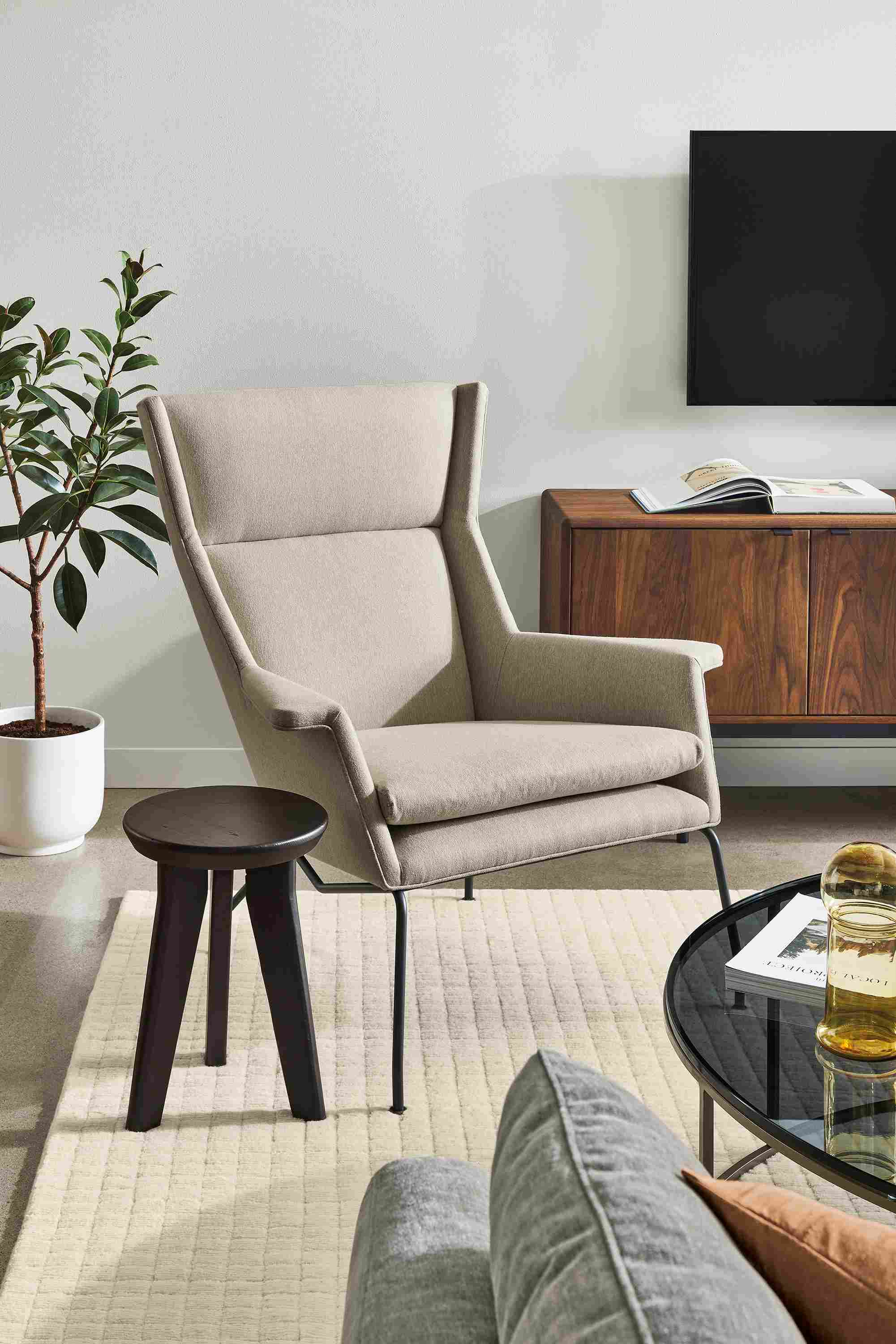 Living room with Aidan chair in Flint Oatmeal, Hollins stool in charcoal and Hensley media cabinet in walnut.