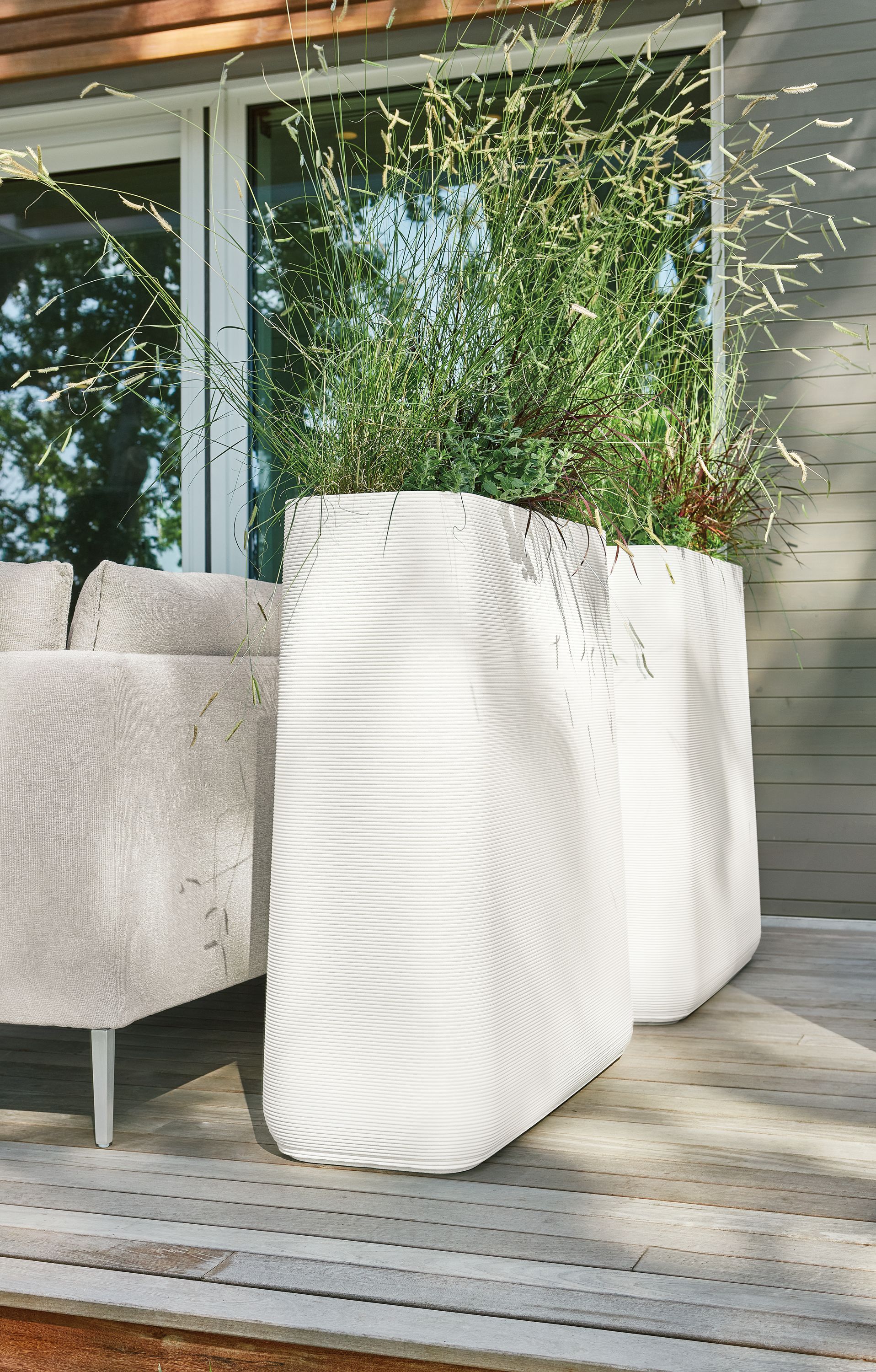 Detail of 2 Ajax planters in white beside outdoor sofa.