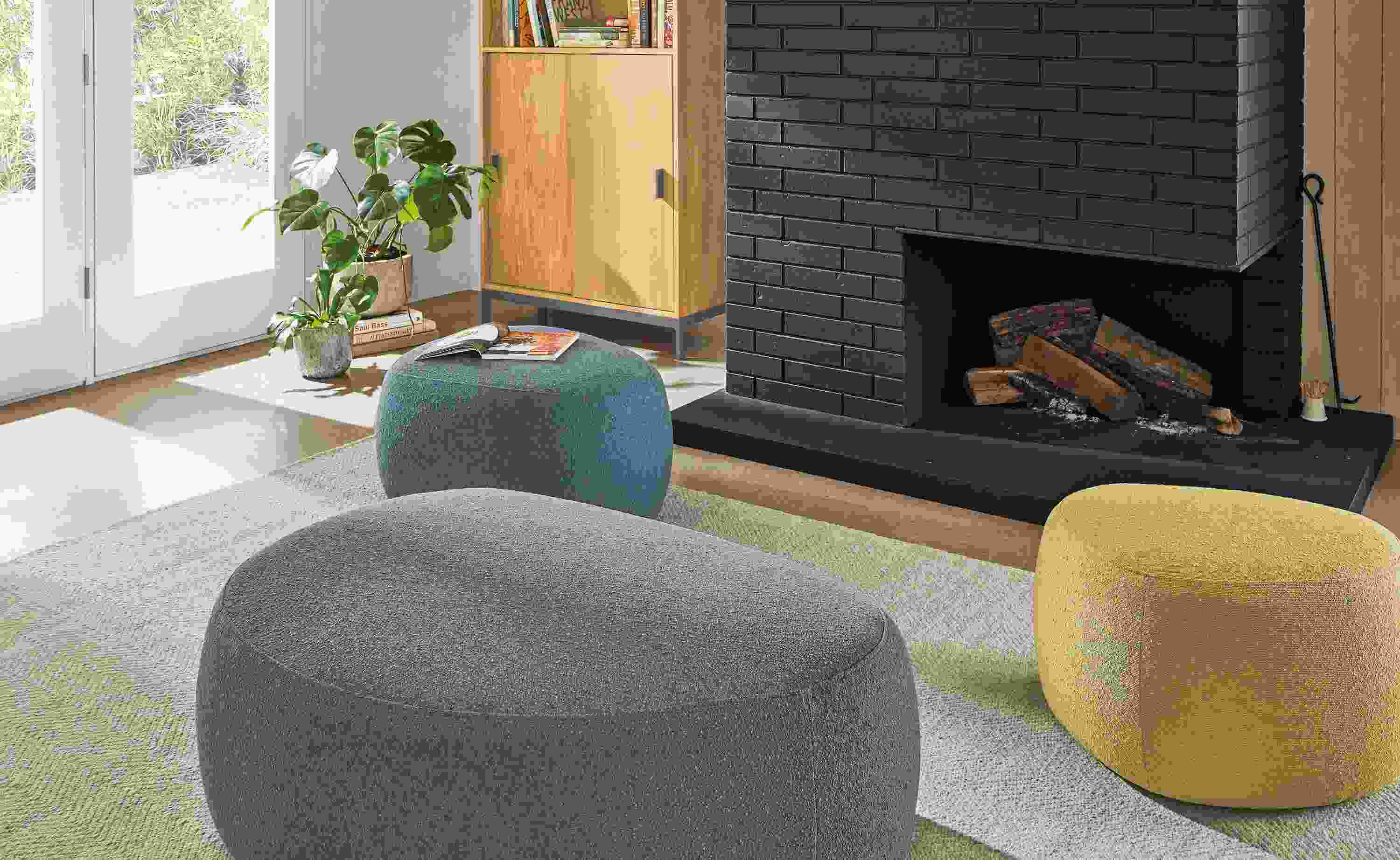 Detail of 3 Asher ottomans in Declan haze, moss and ocean fabrics beside a fireplace.