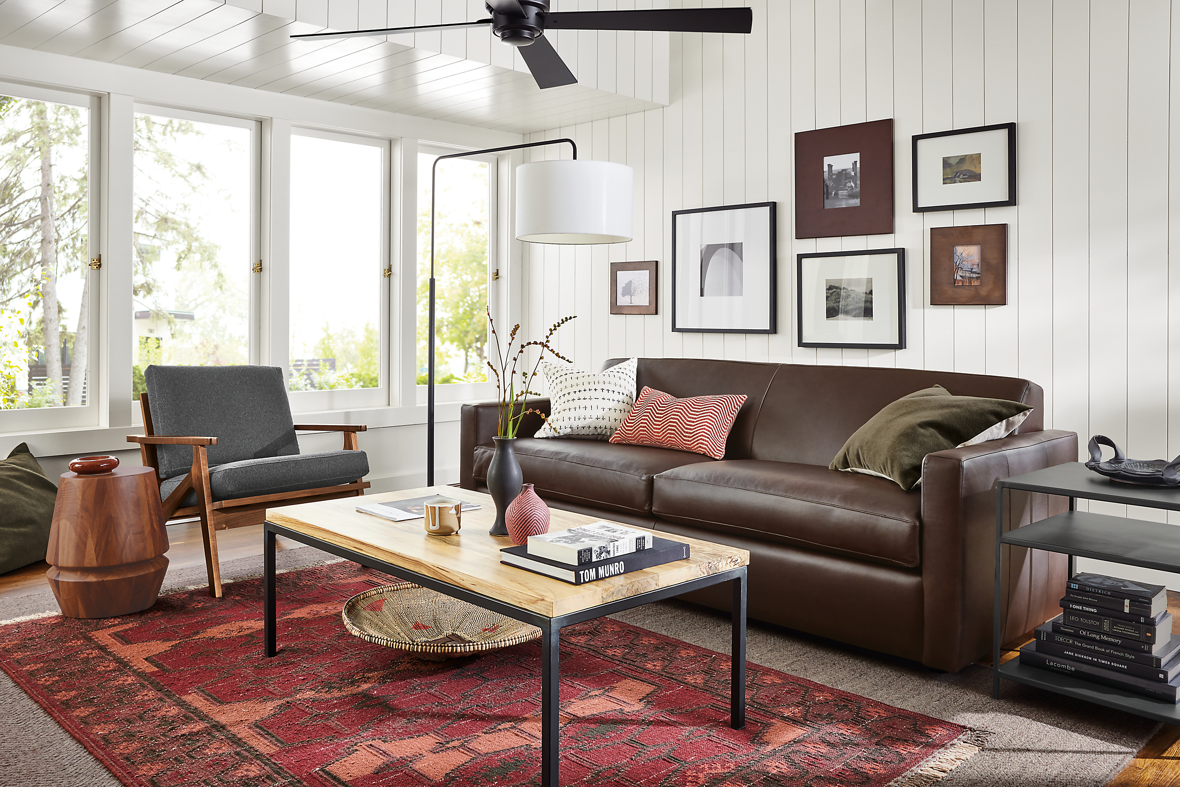 Living room with 84 wide Alex sofa in Laino Coffee leather, Sanna chair in flint charcoal and Tamsa 5 by 8 rug in rust.