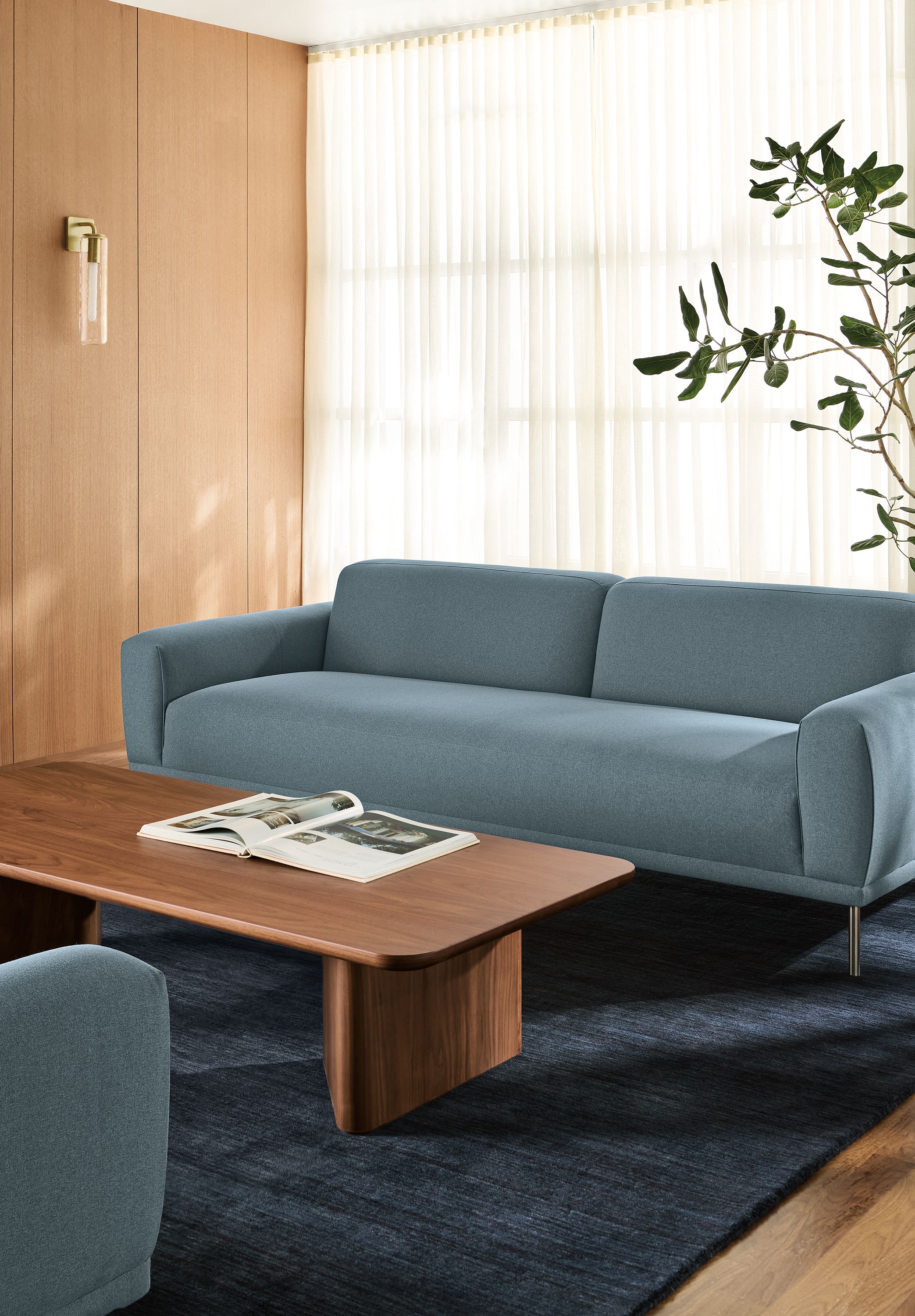 Office lobby with 2 Ali 94-wide bench cushion sofas in Myers Slate, Carver coffee table in walnut and nomad rug in indigo.