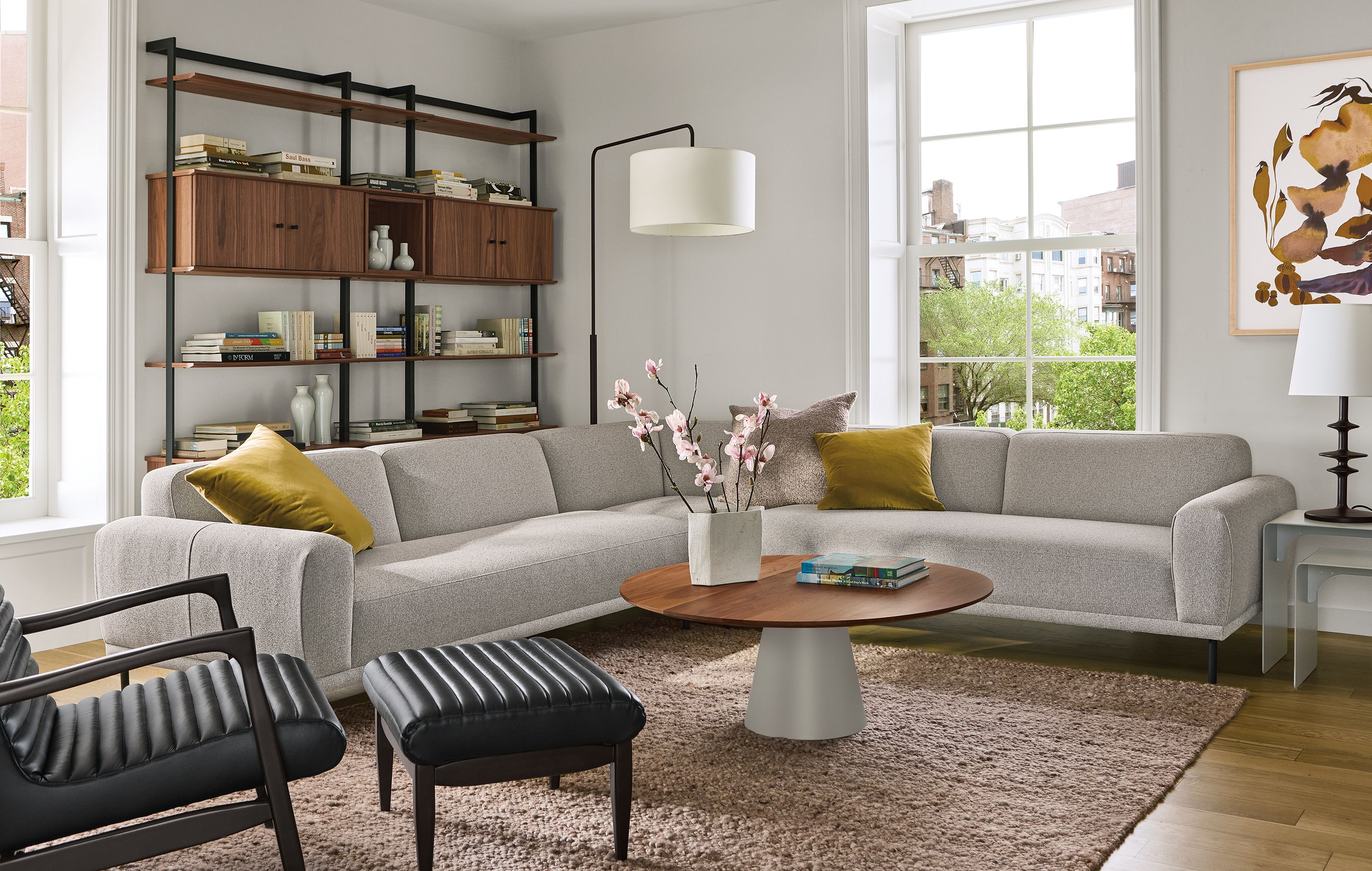 Living room with Ali 117 by 117 sectional sofa in tatum bone and Callan chair and ottoman in Pesaro Black leather.