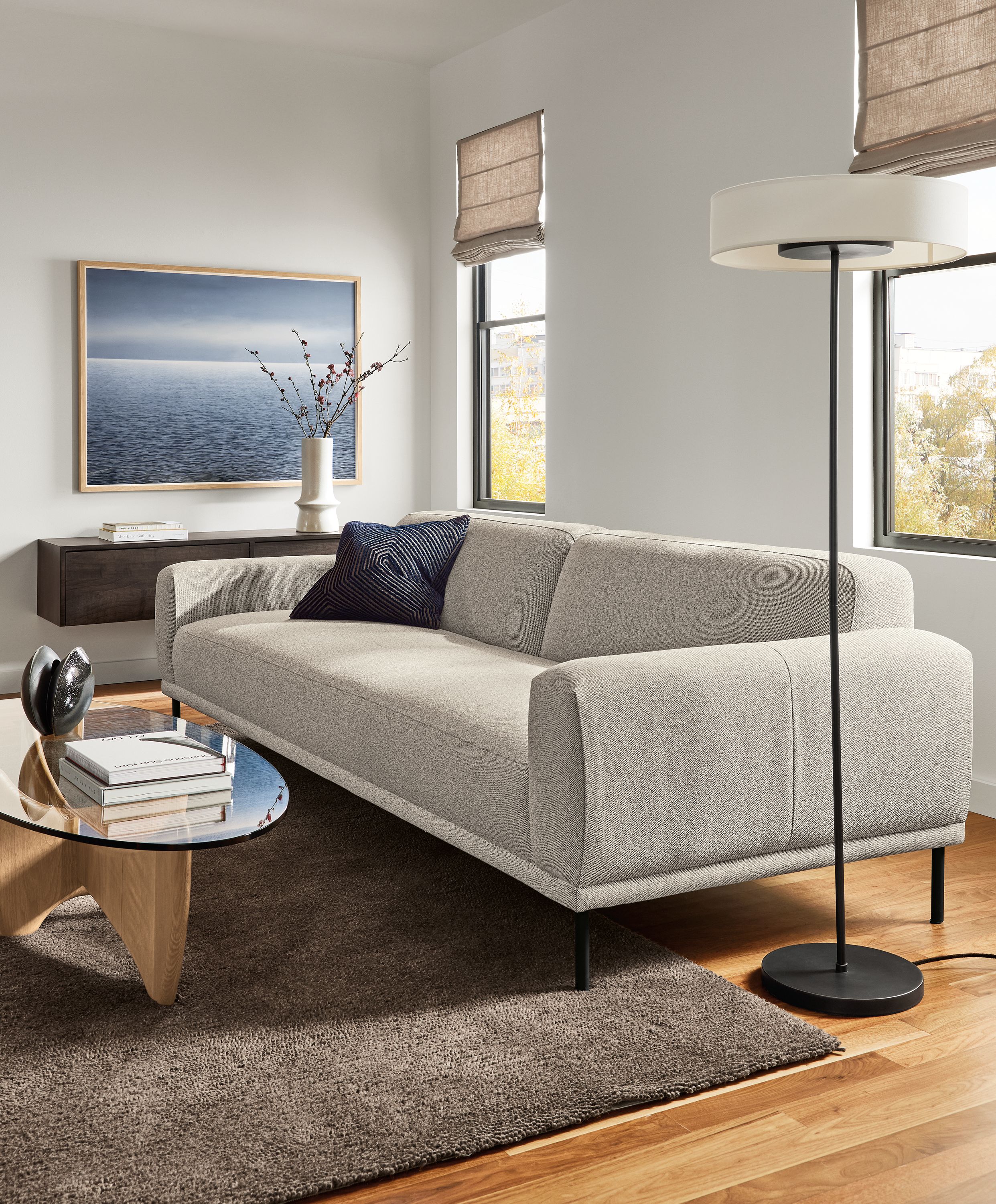 Living room with Ali 104-wide bench cushion sofa in Tatum Bone and Sanders oval coffee table in rye on red oak and clear glass.