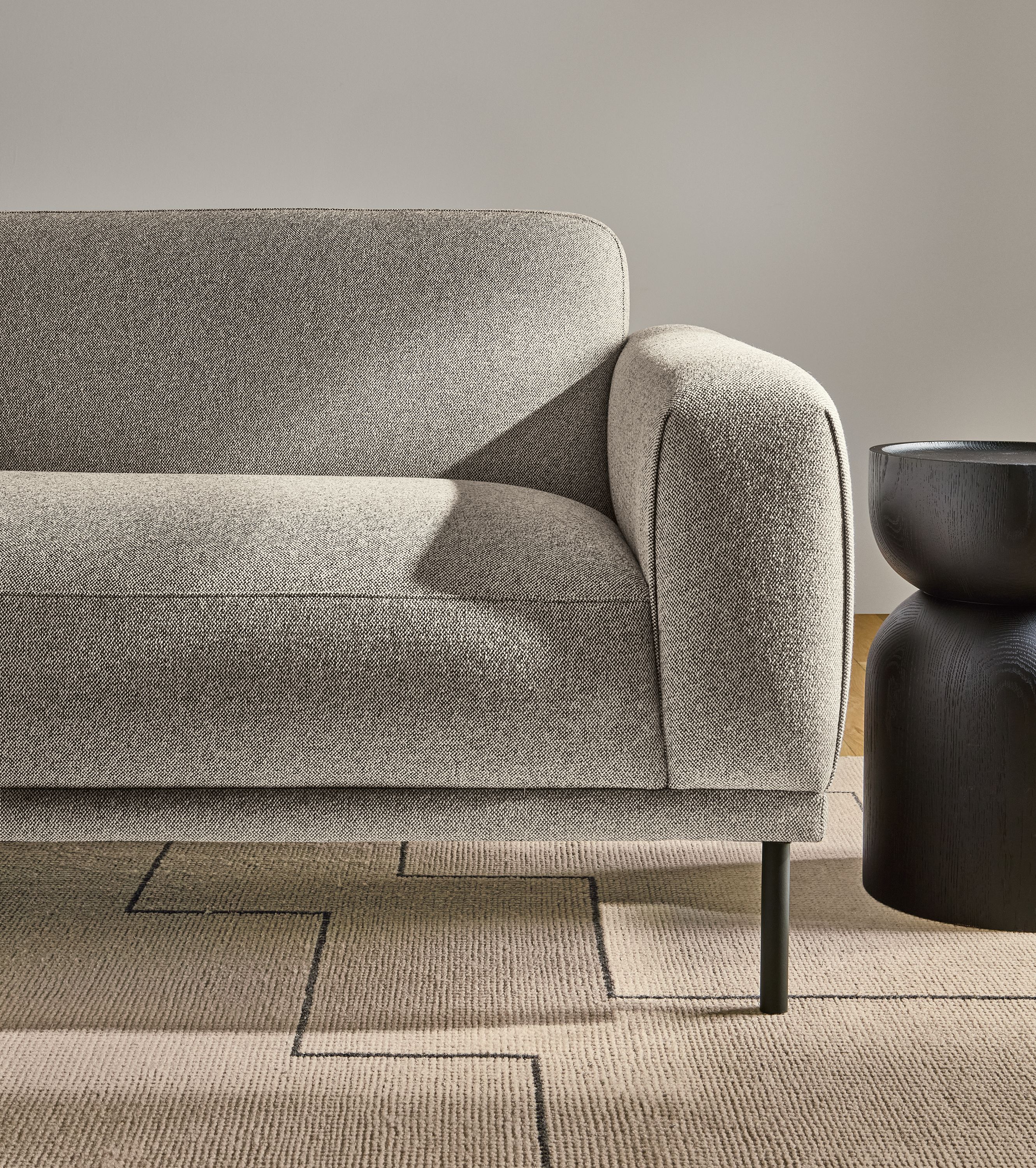Detail of an Ali 94-wide bench cushion sofa in Tatum Bone and a Nyla stool in charcoal stained oak.