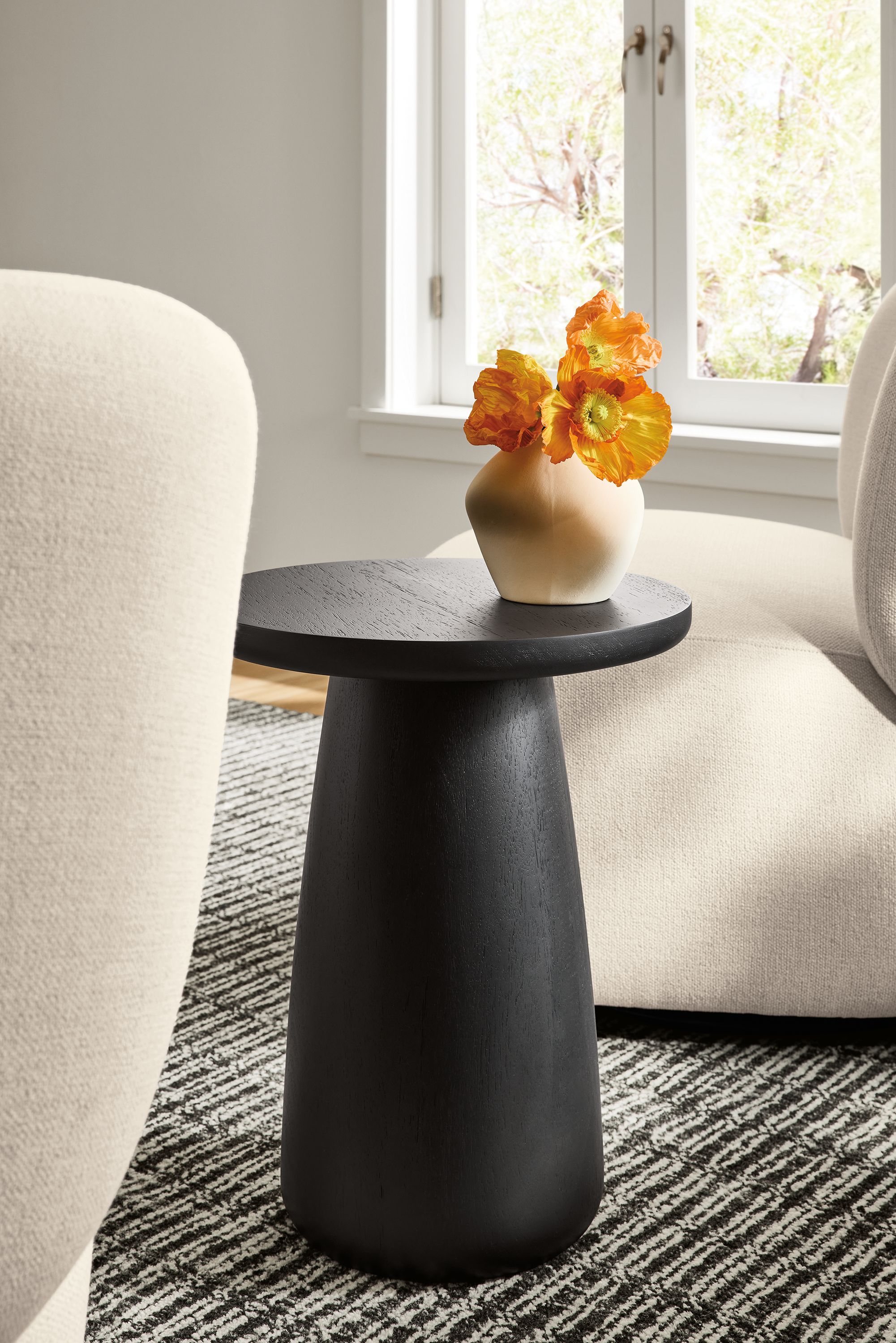 Alma 14-diameter table/stool in Tzalam wood with charcoal stain between 2 Rory swivel chairs in Tepic ivory on a Nera rug in coal.