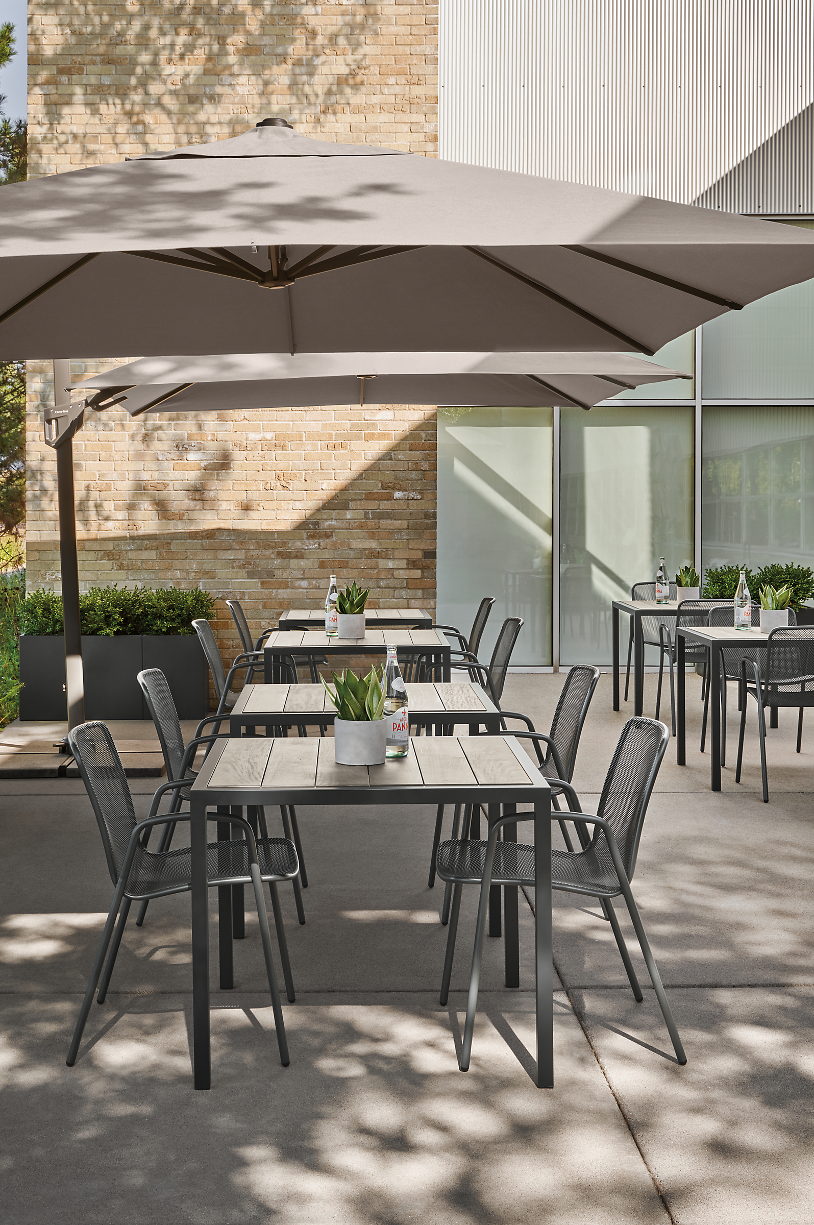 outdoor dining area with alto patio umbrella, montego tables in aged ash, aruba chairs.