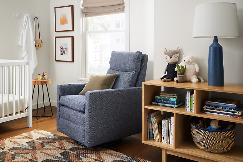 Ambry Swivel Glider in Arin Navy in kids room with white Aster crib and Dahl bookcase.