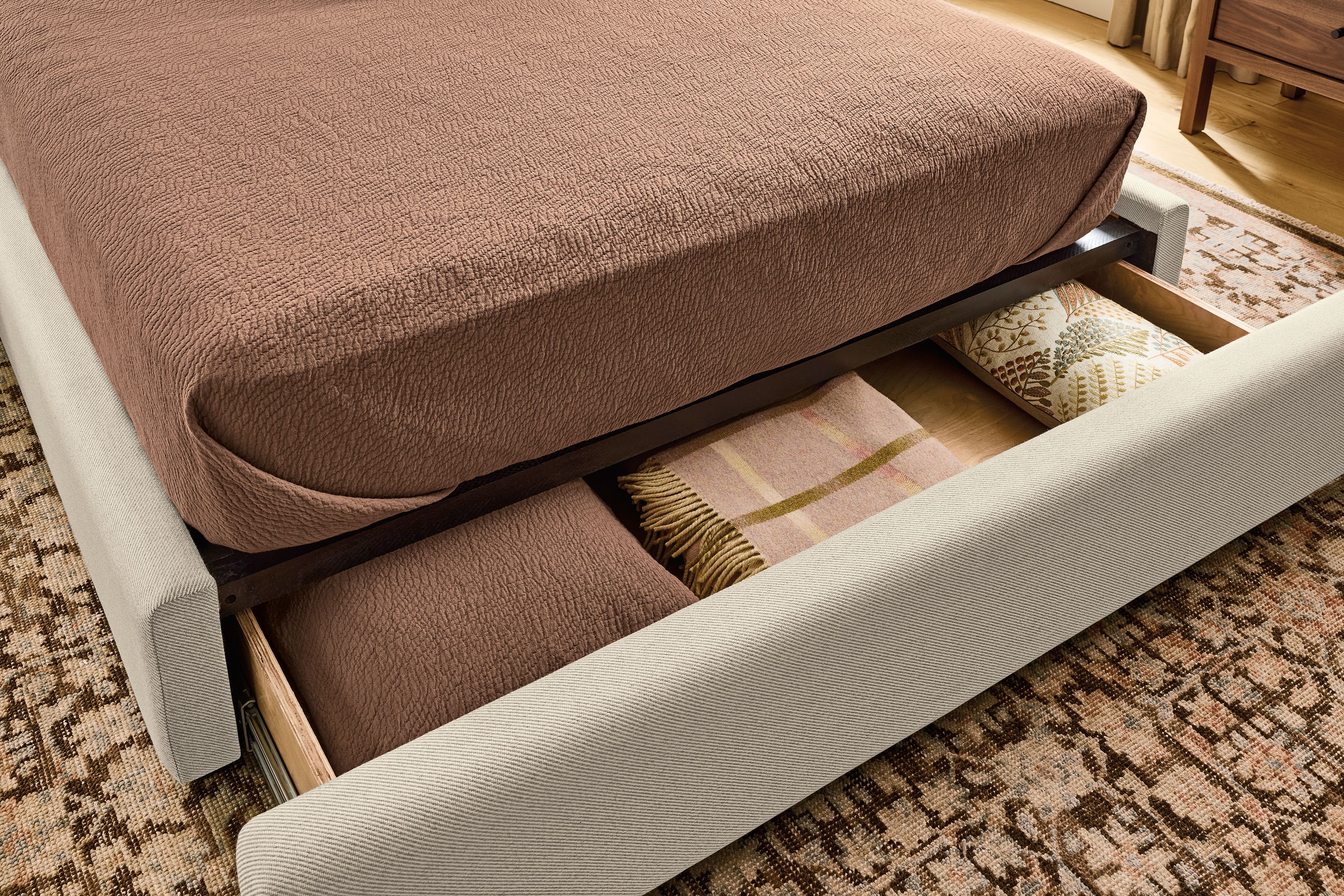 Detail of an open drawer on an Amelia Queen low storage bed in Derry flax and Thea coverlet and sham in brick.