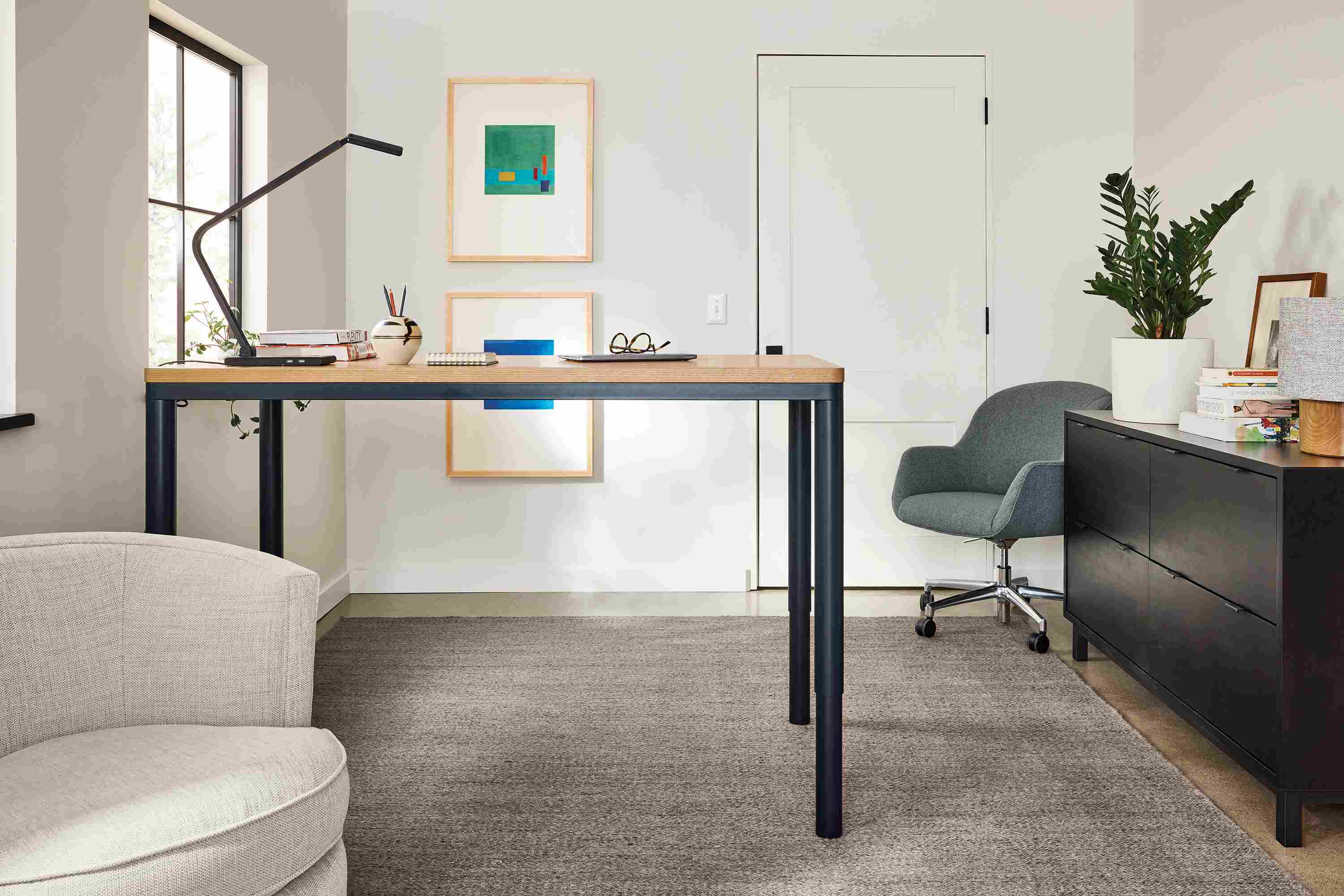Home office with Ames adjustable standing desk in rye on red oak and graphite shown in raised postion and Avilia rug in foxhound.
