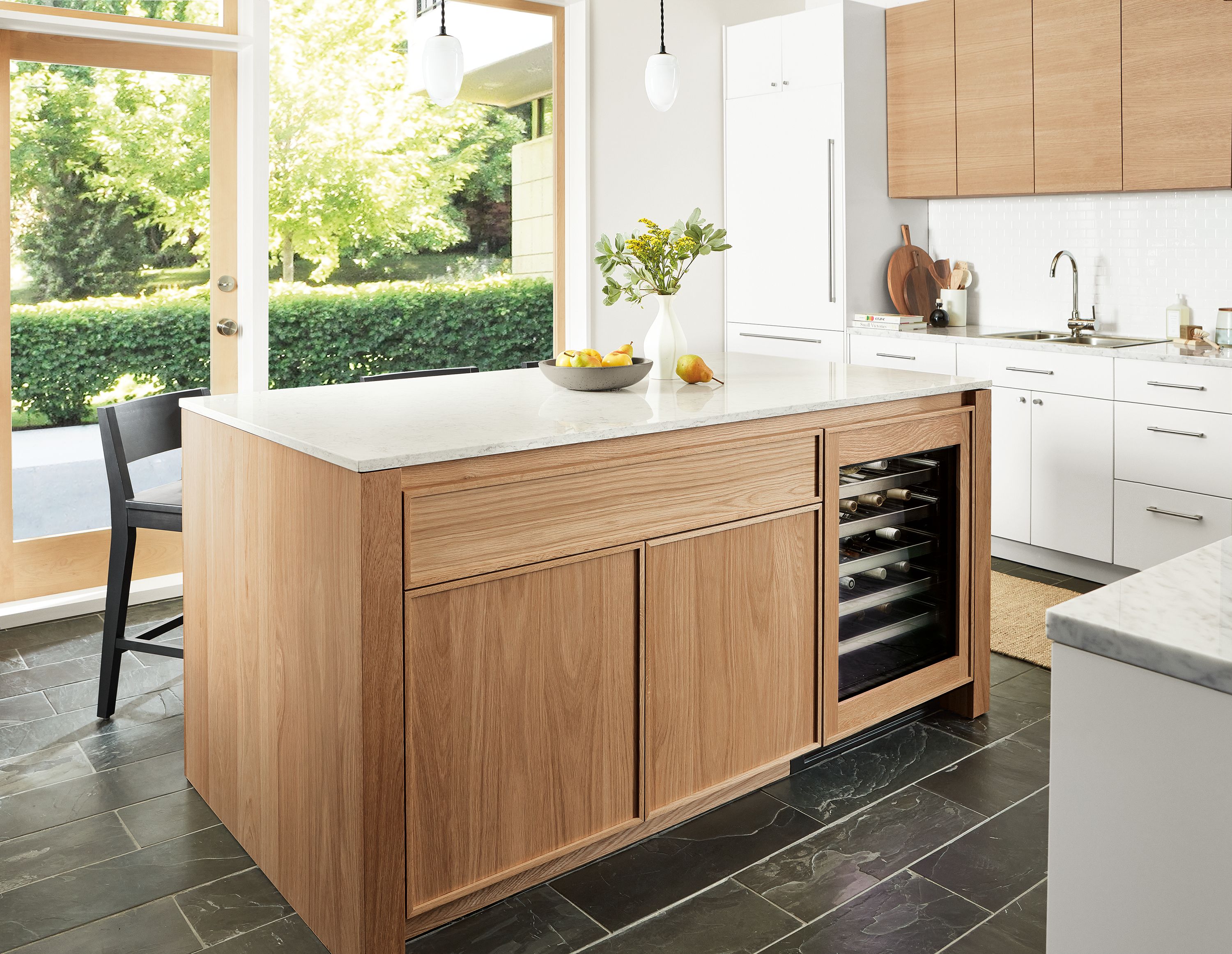 Kitchen with Amherst 72-wide kitchen island in rye on red oak with glass door fridge and polar pendant lights.