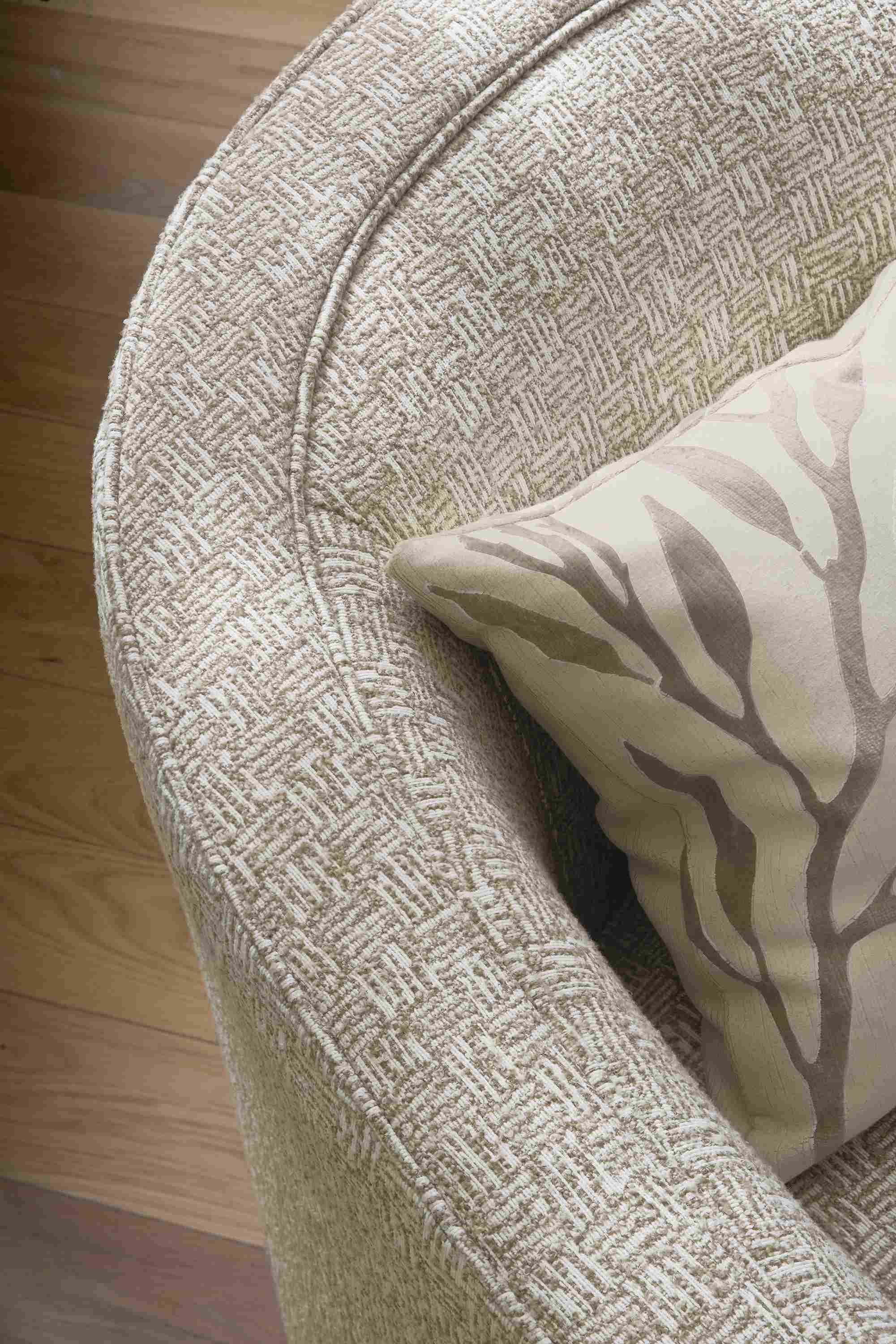 High-angle detail view of an Amos swivel chair in Wexford Flax and Liana 20 by 13 pillow in snow.