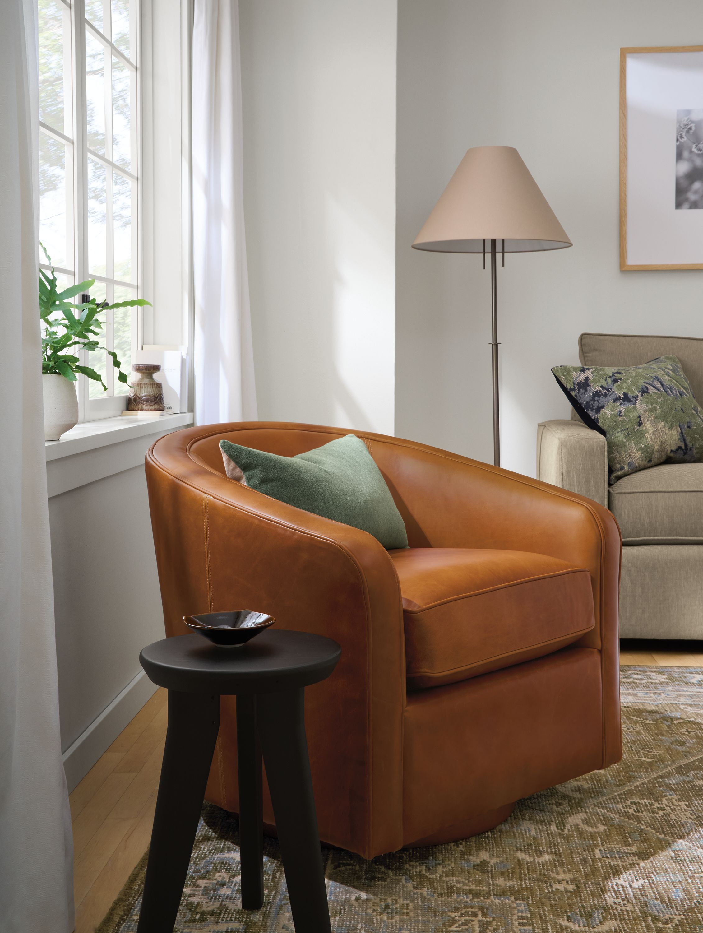 Living room with Amos swivel chair in Vento Cognac leather, Veda rug in Moss and Hollins stool in reclaimed charcoal pine.