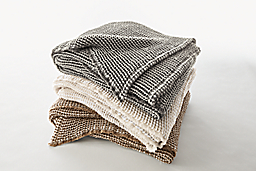 Detail of Anika throws, stack of three in charcoal, off-white, taupe.