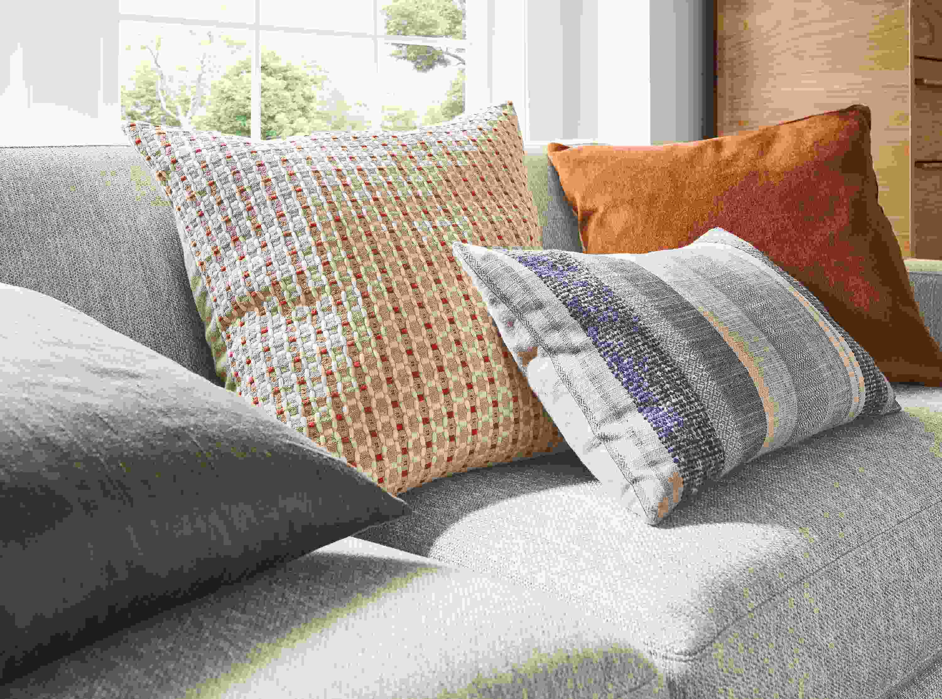 Detail of ansley pillow in brick, silk pillow in charcoal, tetra pillow in ink and wool velvet pillow in rust.