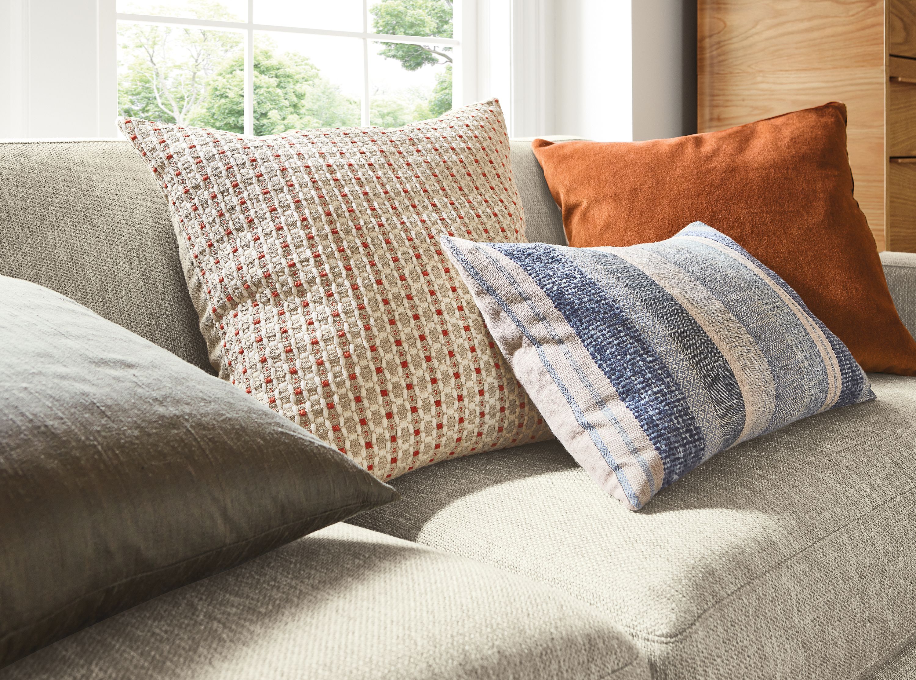 Detail of ansley pillow in brick, silk pillow in charcoal, tetra pillow in ink and wool velvet pillow in rust.