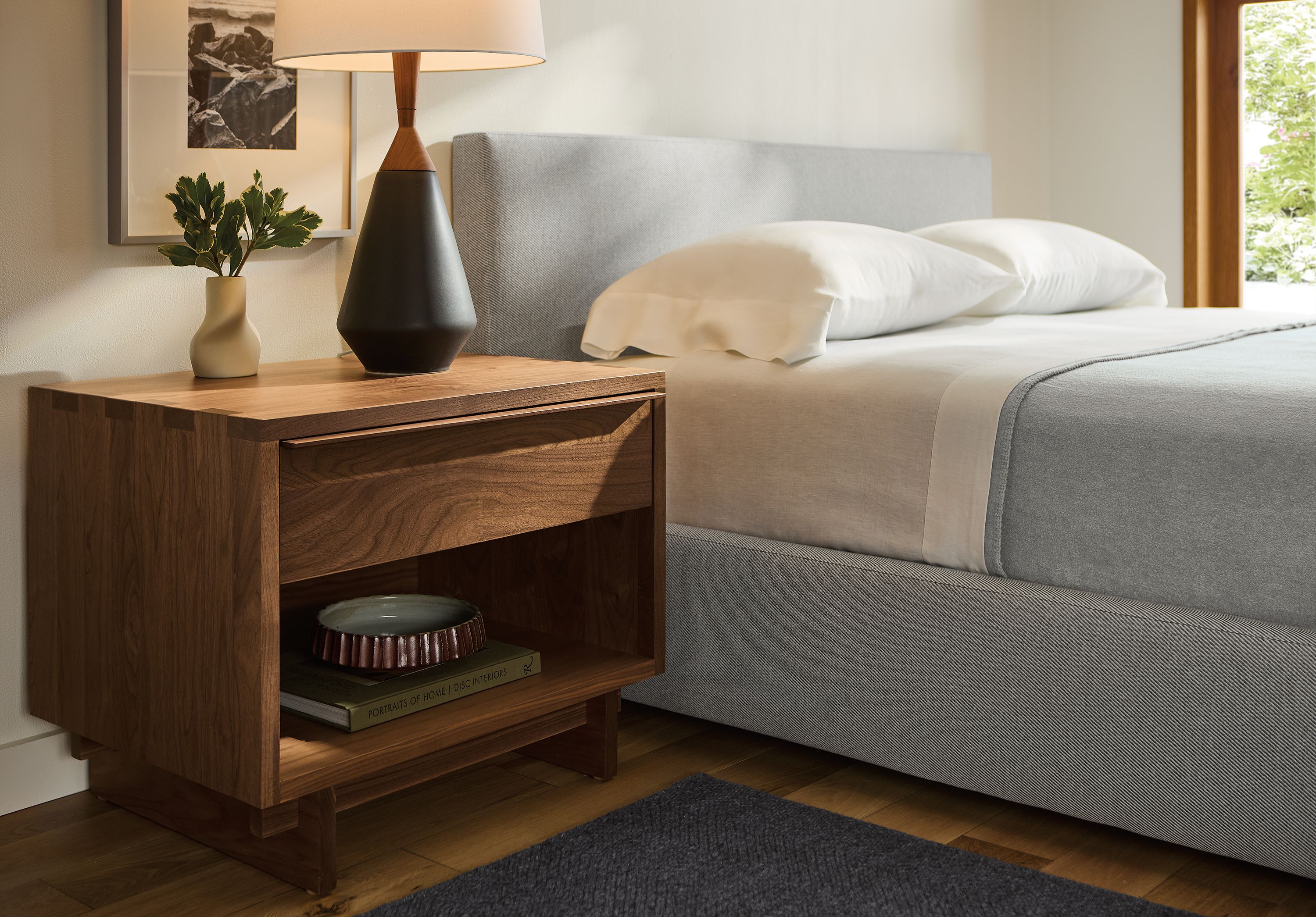 Bedroom with anton nightstand in walnut, wyatt queen storage bed in derry cement and avilia rug in charcoal.