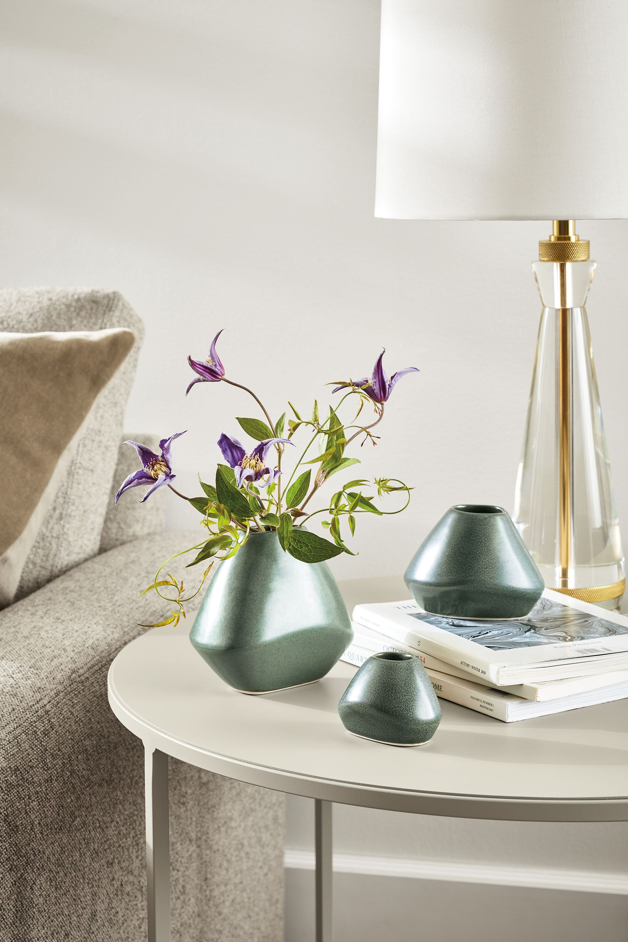 Slim round table with 3 Anya bud vases in Fern in a living room.