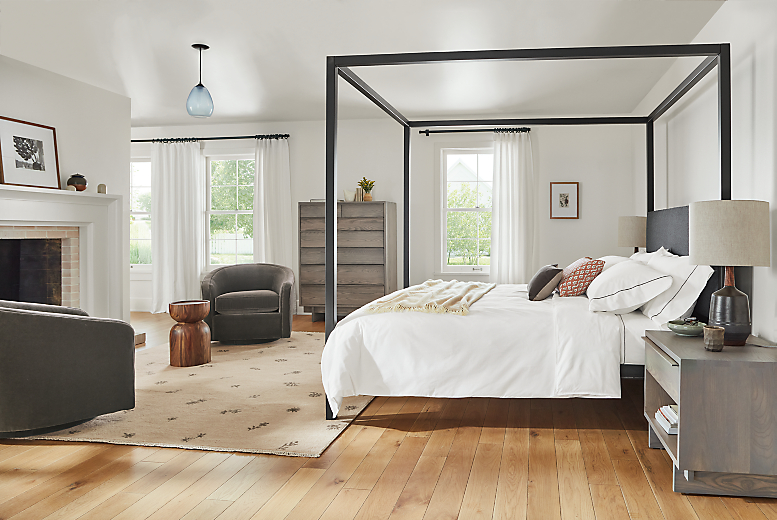 bedroom with fireplace, architecture canopy bed, tansy rug, amos swivel chair, anton dresser and anton nightstands.