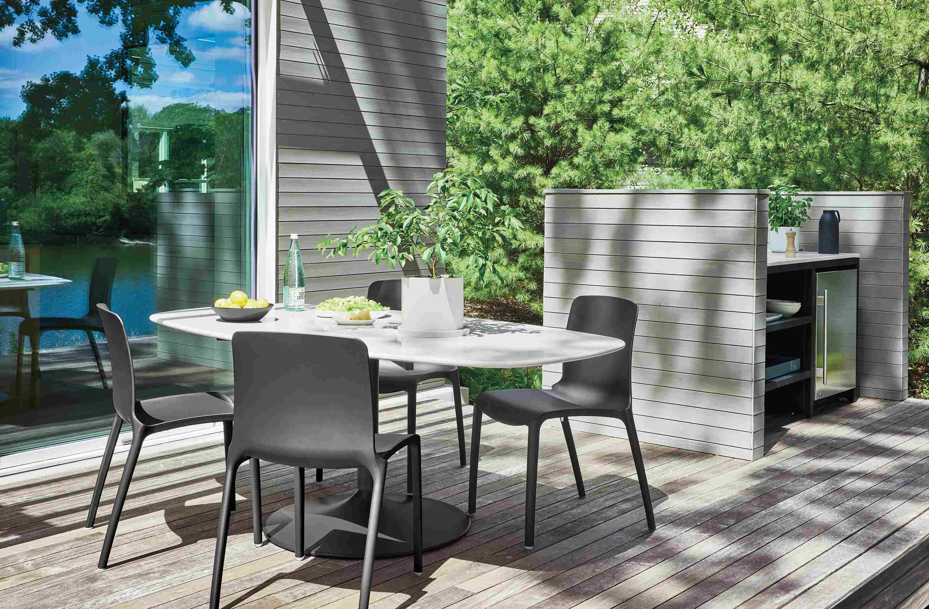 Home deck with Aria 76-wide outdoor boat top dining table in graphite with white quartz top and tiffany side chairs.