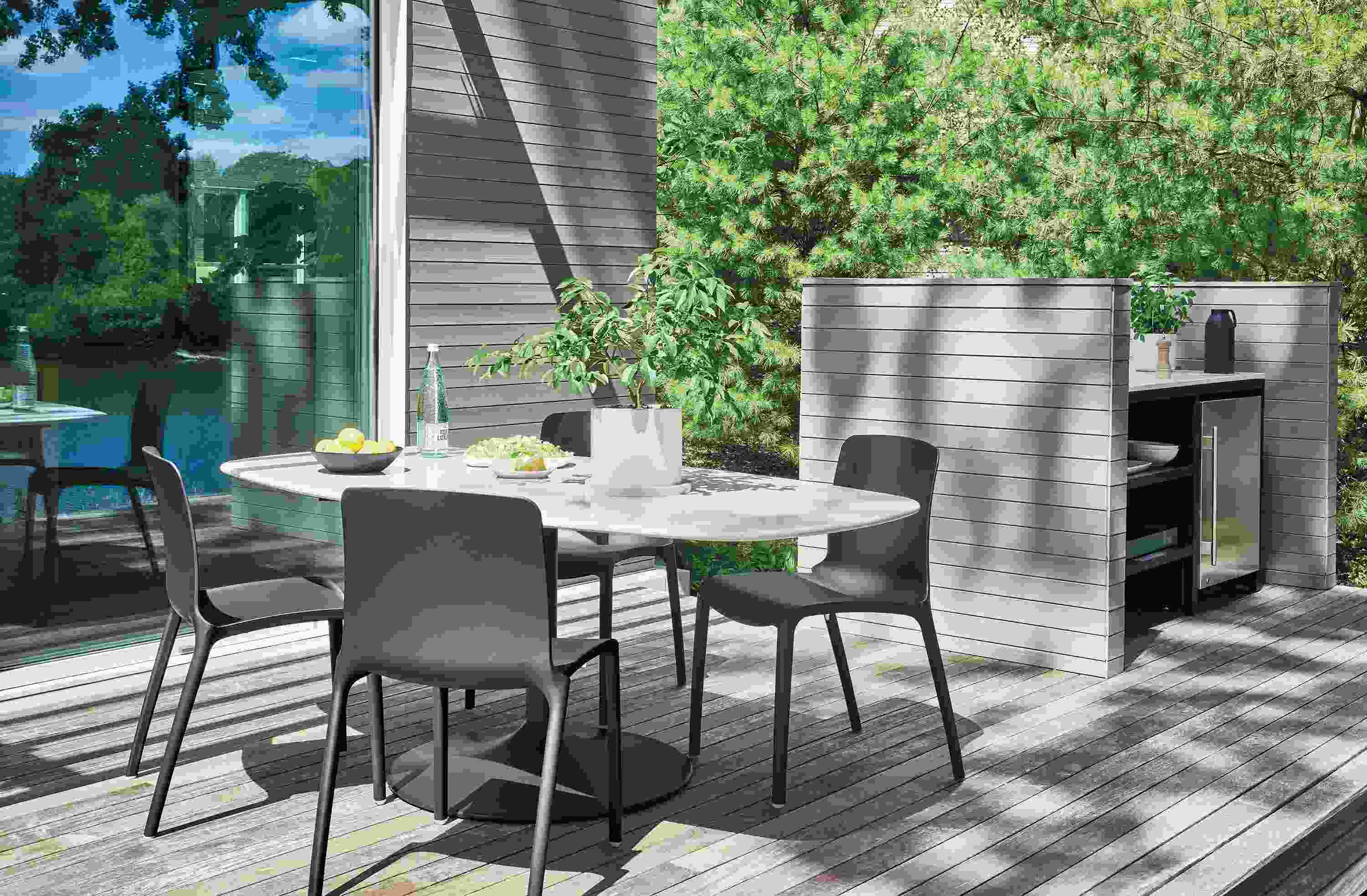 Home deck with Aria 76-wide outdoor boat top dining table in graphite with white quartz top and tiffany side chairs.
