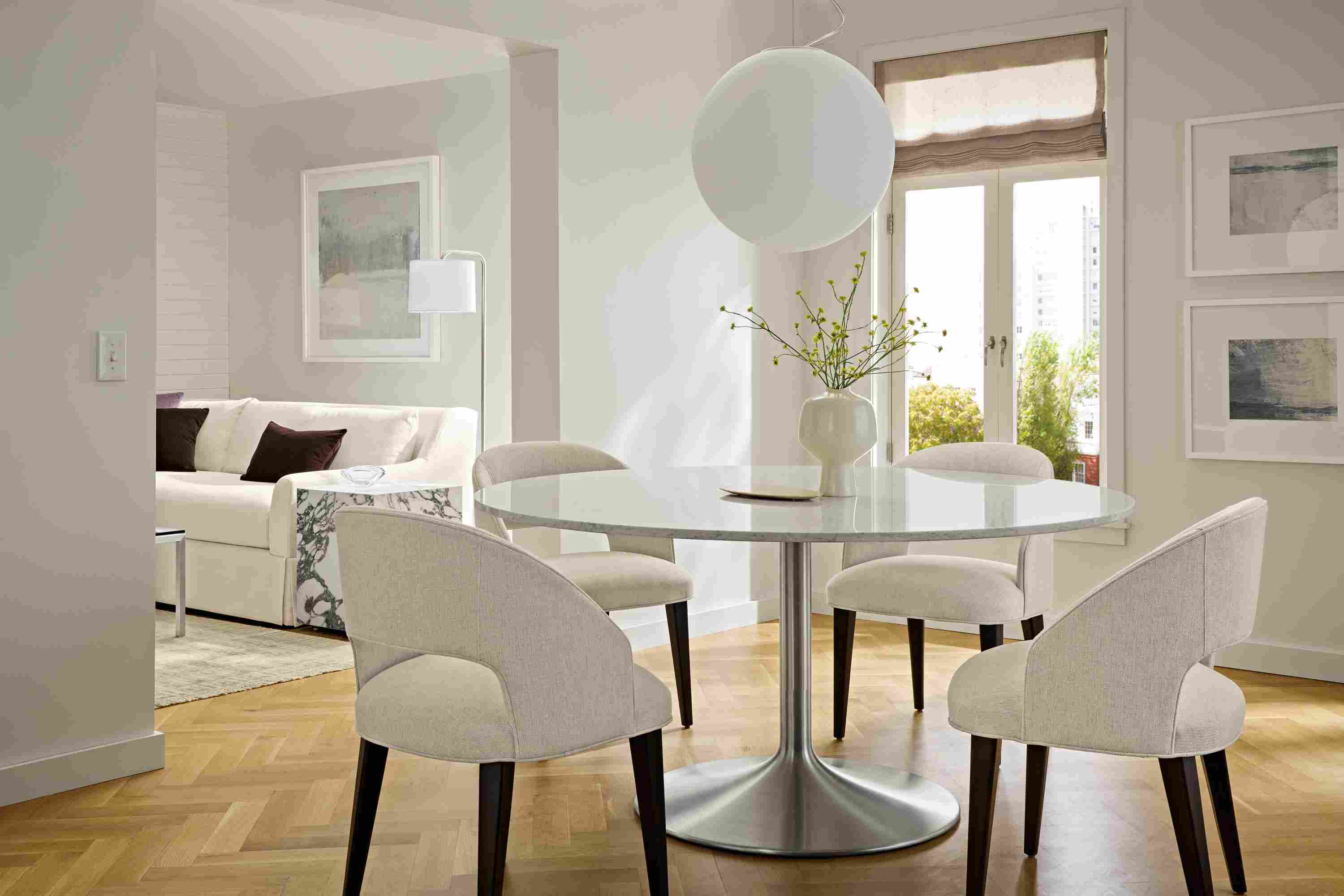 Dining room with Aria 60-round dining table in stainless and marbled white quartz and 4 Esme chairs in Sumner Linen.
