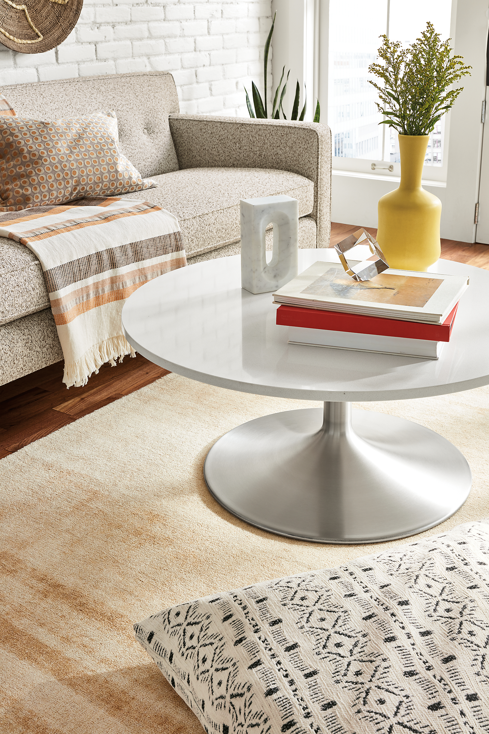 Aria 36-Round Coffee Table in Stainless steel and white quartz top with Andre sofa.