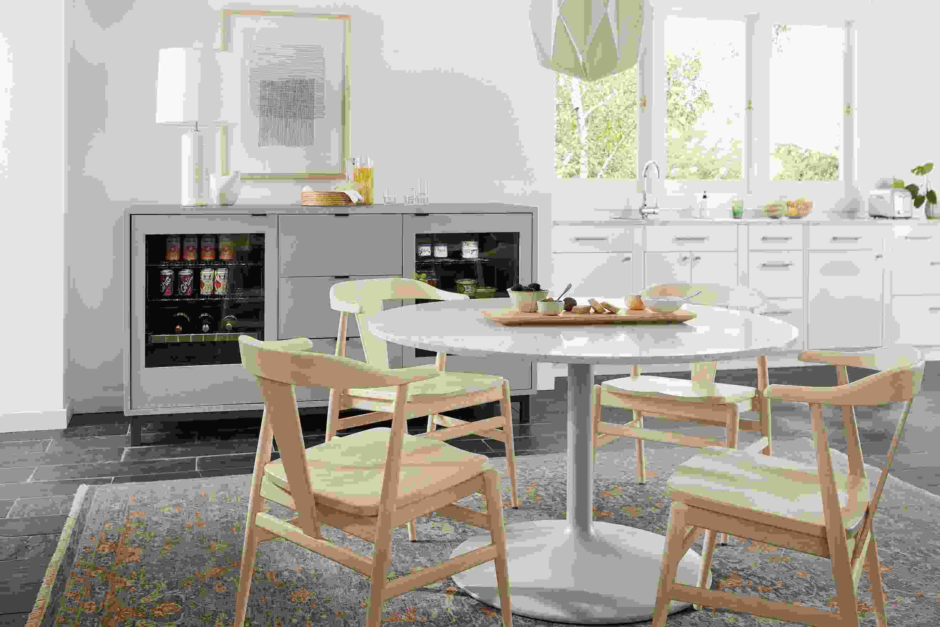 Dining area with Aria 48-diameter table in taupe, Evan arm chairs in sand and 72-wide Copenhagen double fridge cabinet in taupe.