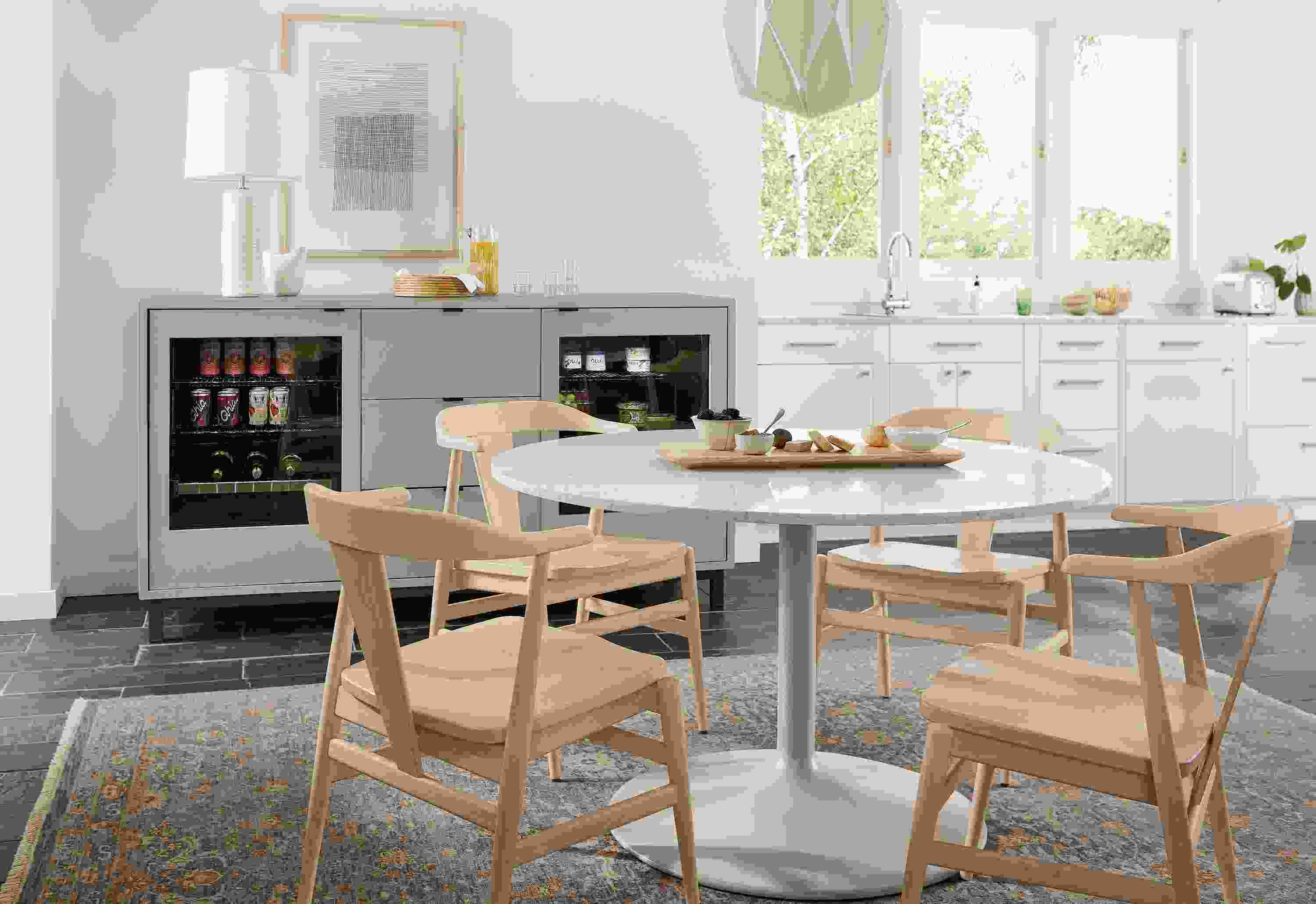 Dining area with Aria 48-diameter table in taupe, Evan chairs in salt and 72-wide Copenhagen double fridge cabinet in taupe.
