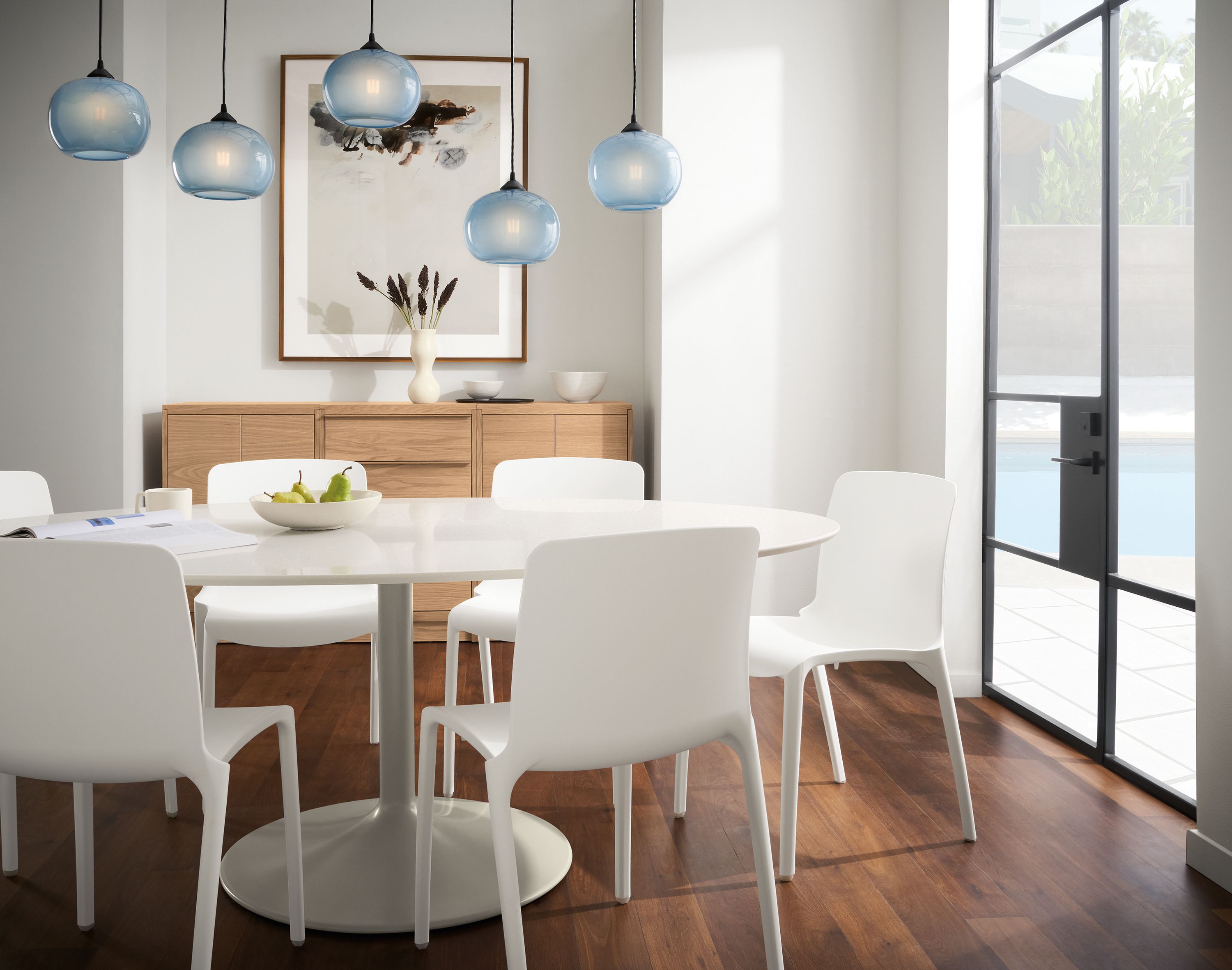 Dining room with white Aria table, Tiffany side chairs in white and gale pendant light set in cloud blue.