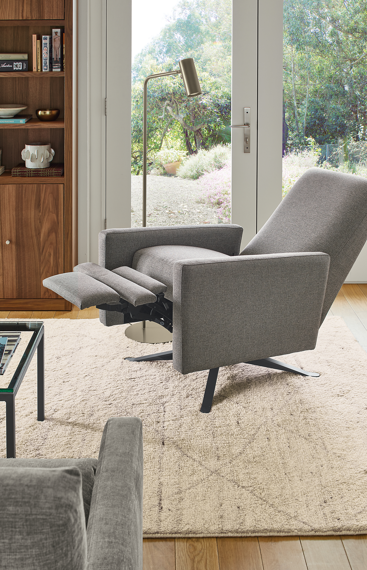 Living area with Arlo Recliner in Sumner graphite fabric and graphite metal base in open position and Kalindi rug in Cement.