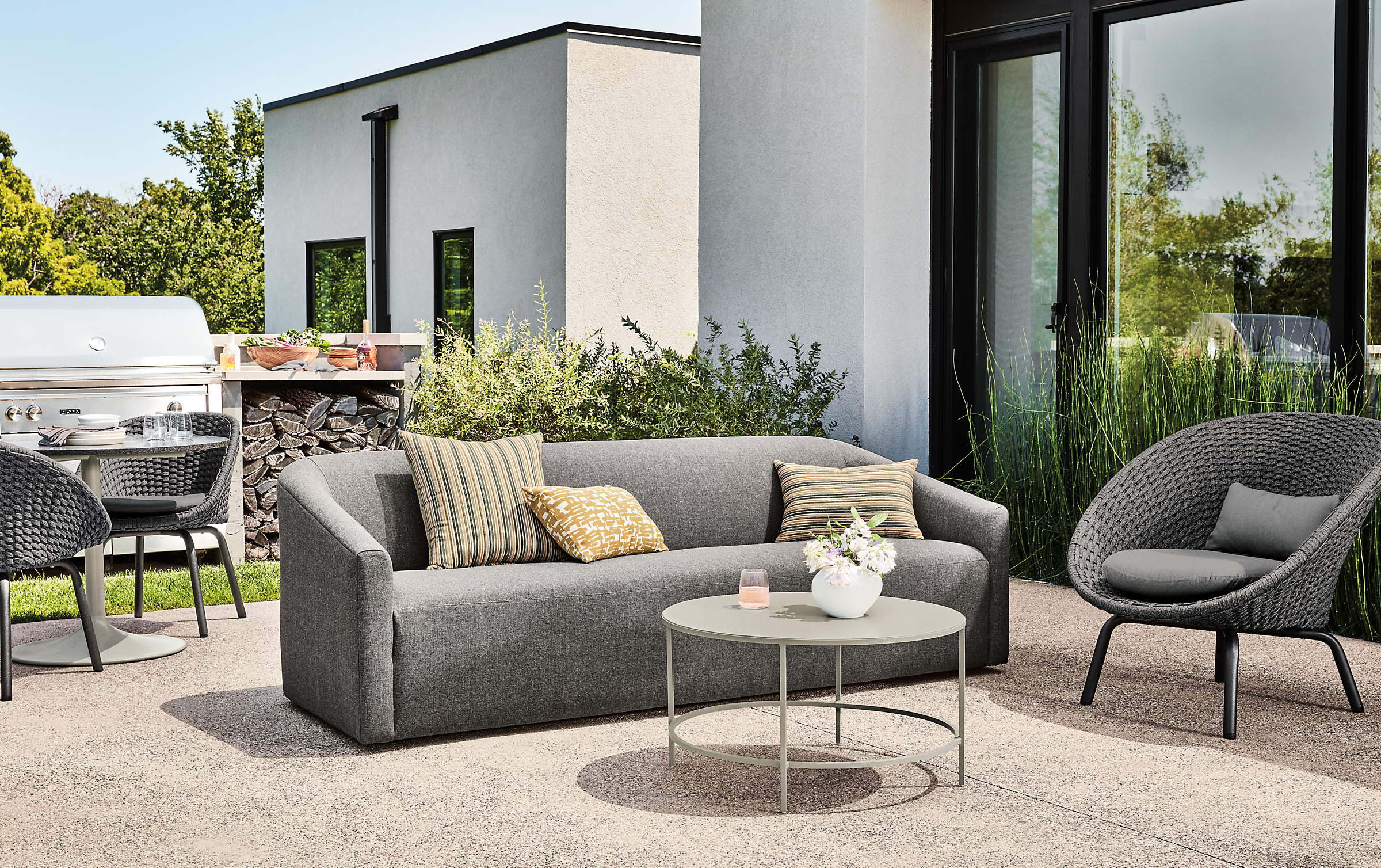 Outdoor patio with Arris sofa in Mist Charcoal, Flet Chair in slate and Slim coffee table in taupe.