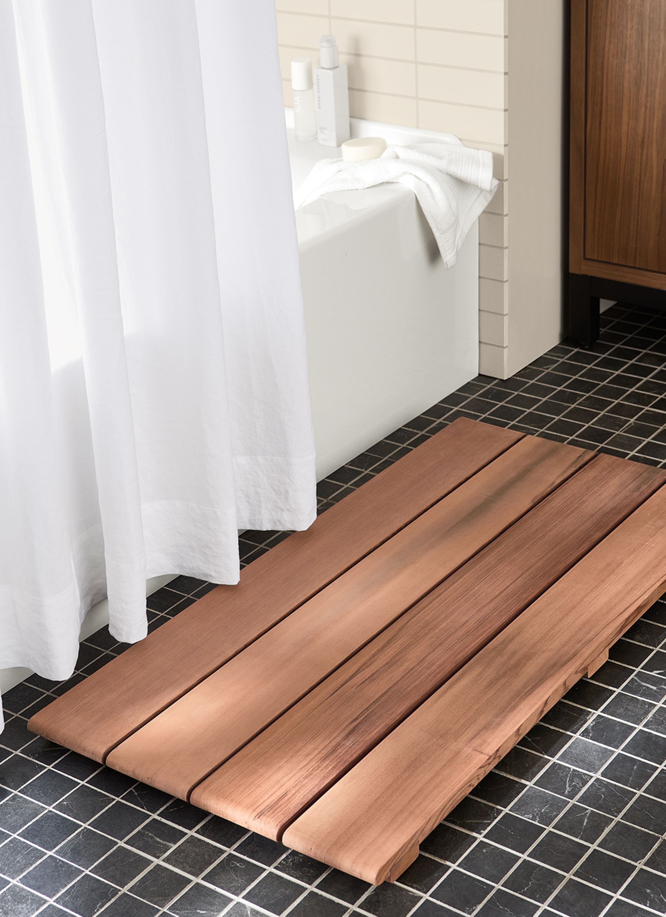 detail of artemis bath mat in redwood beside bathtub.