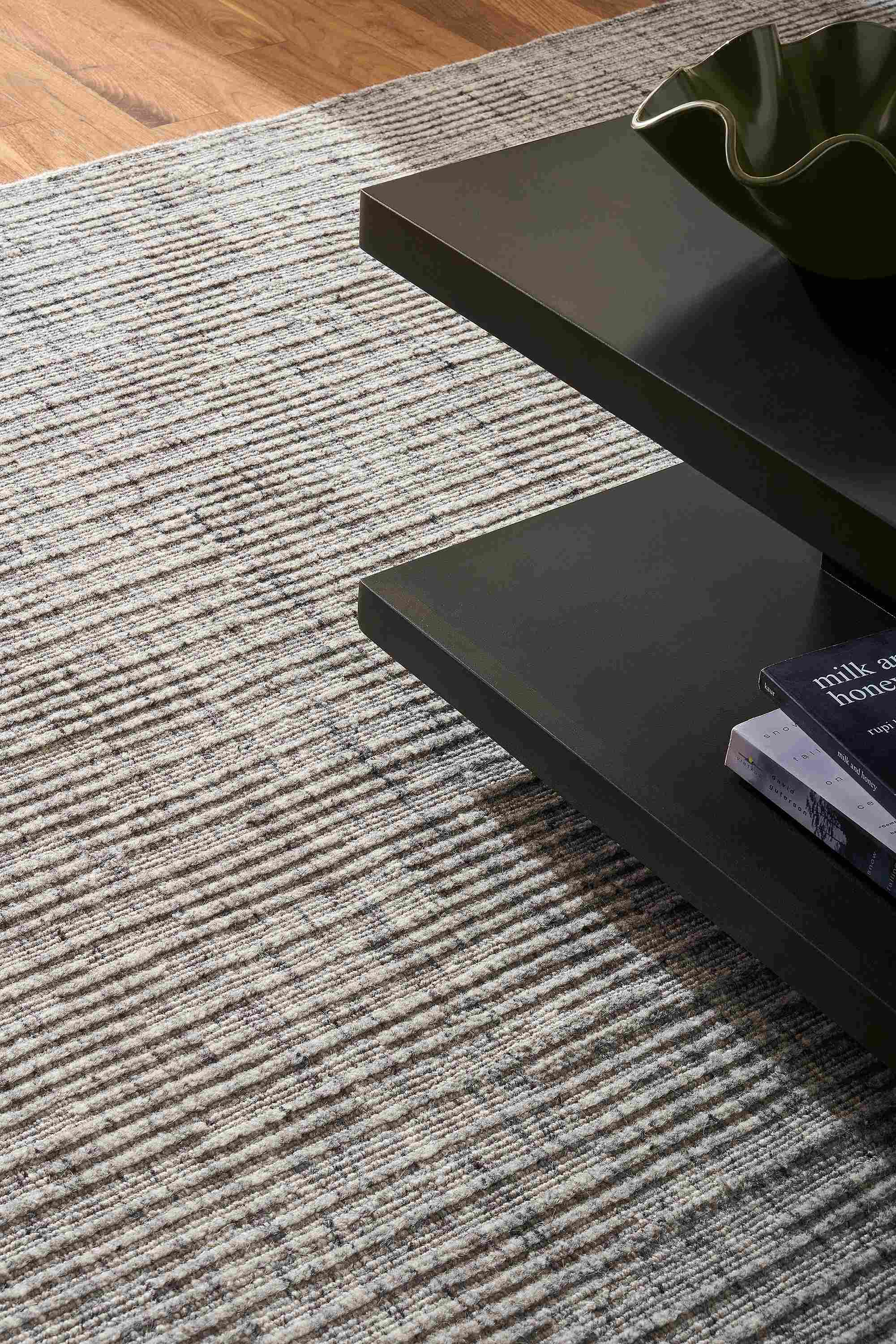 Detail of Artis 8 by 10 rug in grey and corner of graham coffee table in charcoal.