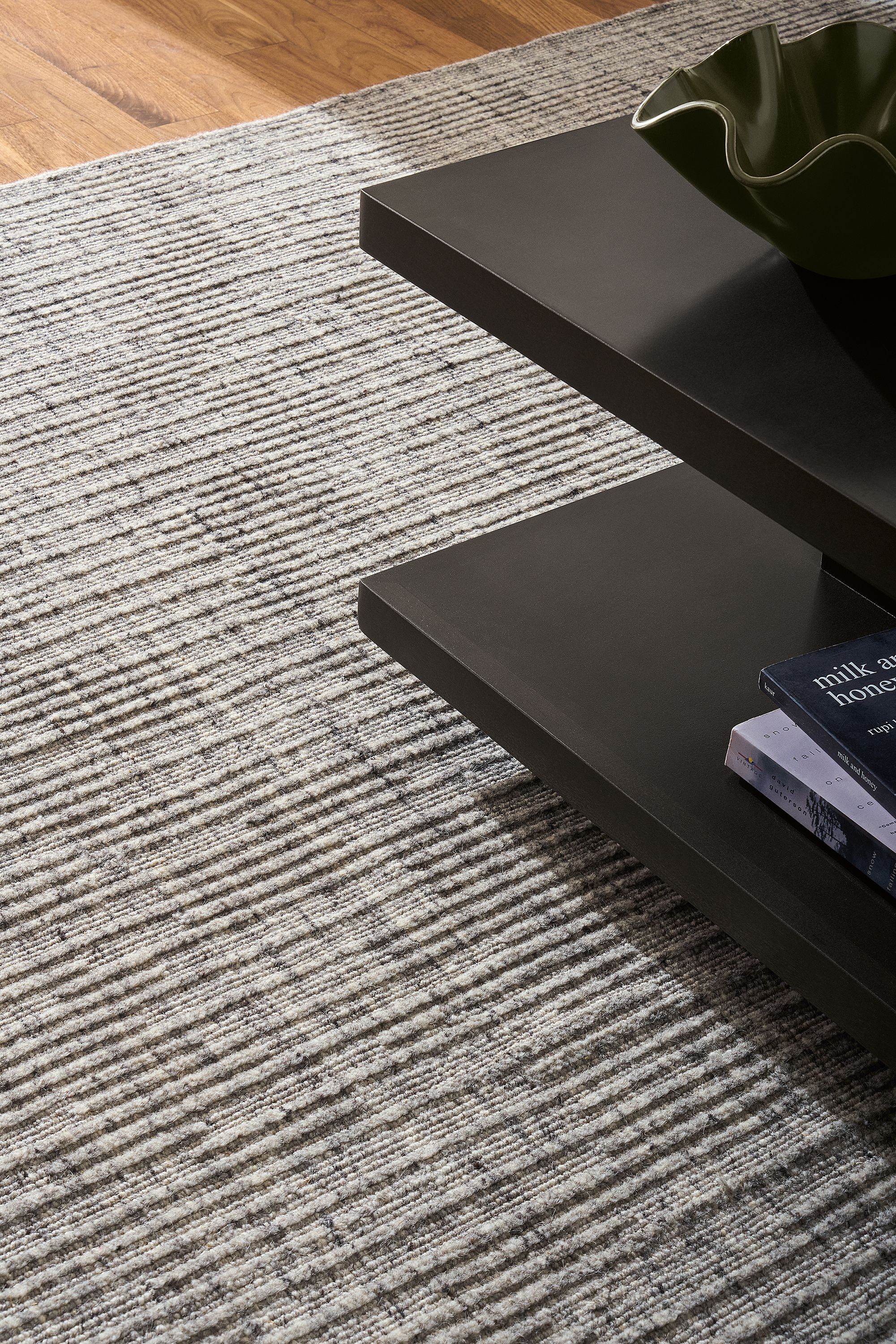 Detail of Artis 8 by 10 rug in grey and corner of graham coffee table in charcoal.