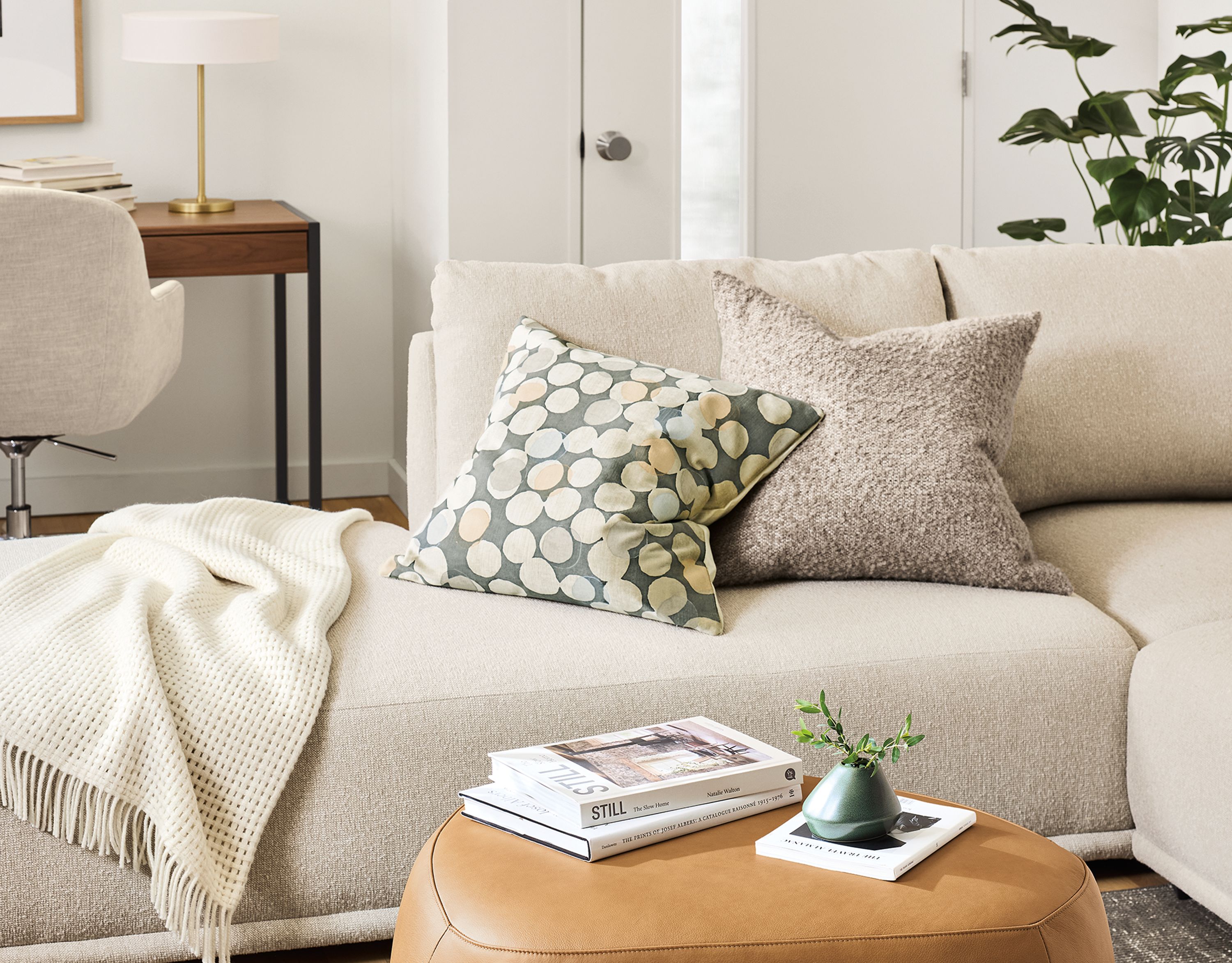Living room with detail of 2 asher ottomans in laino camel leather, samar rug in charcoal and fia sofa.
