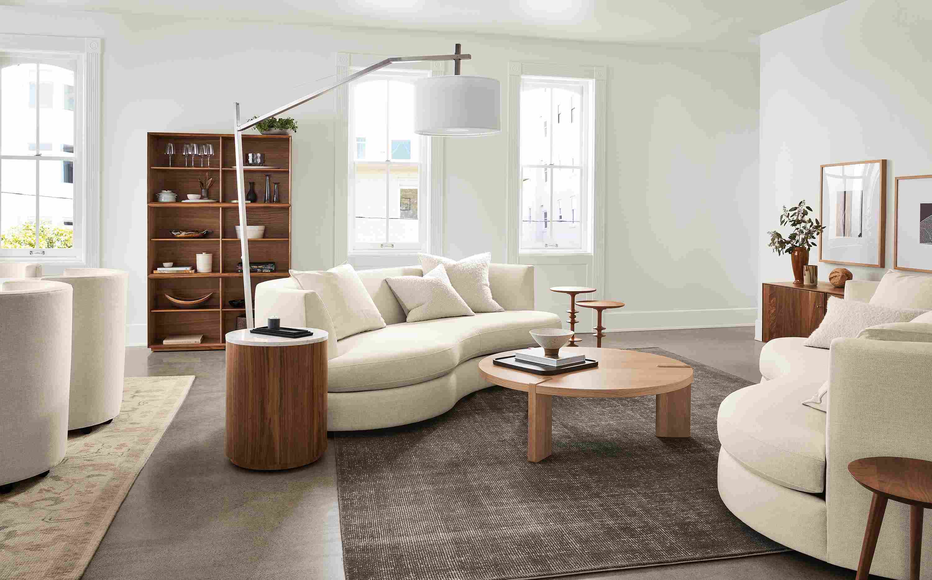 Living room with 2 Astaire Bench Cushion Curved Sofas in Sumner Ivory and Hanover 48-round Coffee Table in rye on red oak.