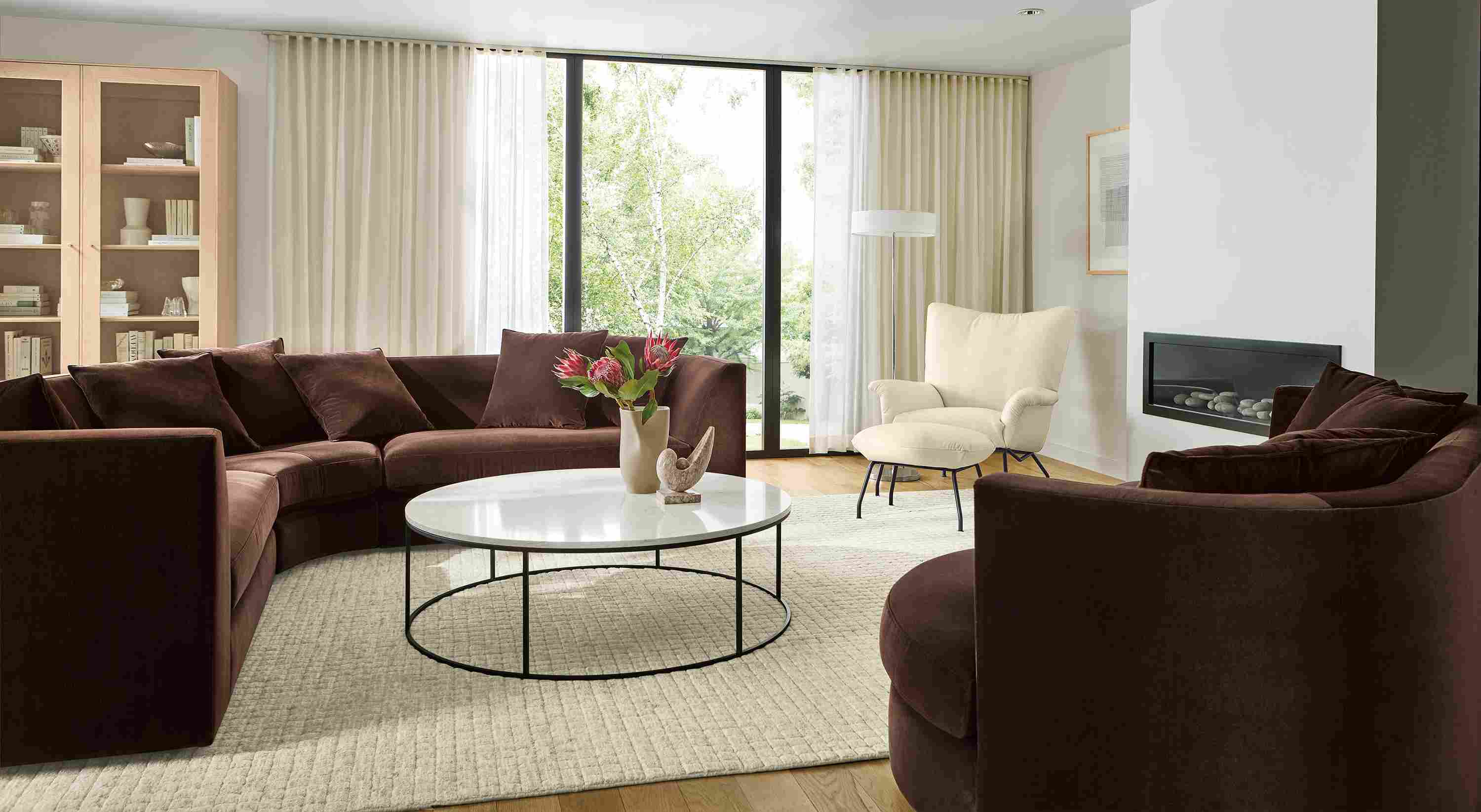 Living room with Astaire sectional and curved sofa in Redding Espresso and Tyne round coffee table with marbled white quartz top.